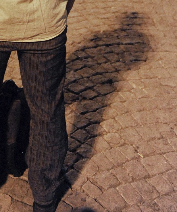 detail of the legs of the standing man and their shadow on the pavement