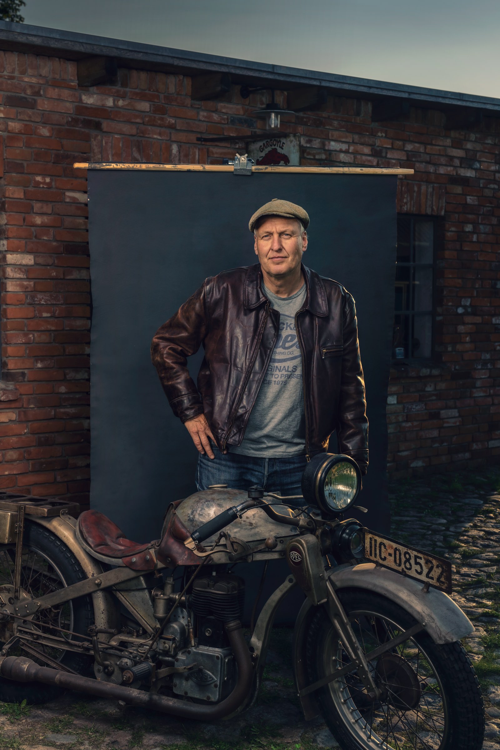 Ein Mann steht vor einem grauen Hintergrund, vor ihm ein Opel-Motorrad