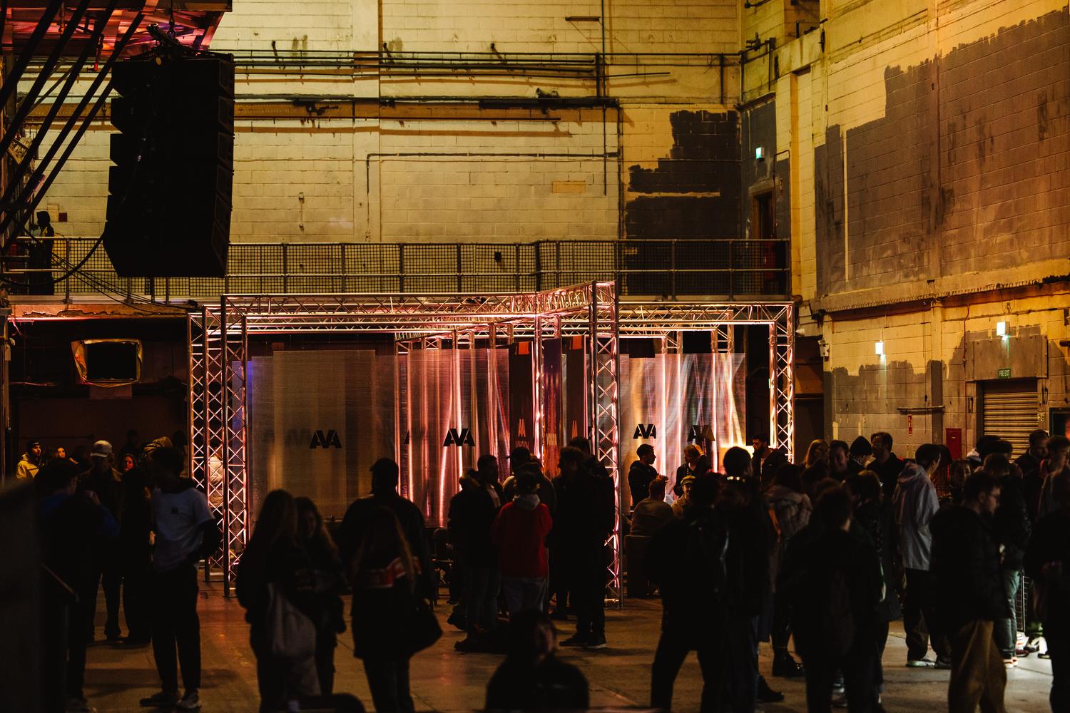 Crowd gathered inside Printworks during AVA London conference with AVA branded installation and lighting.