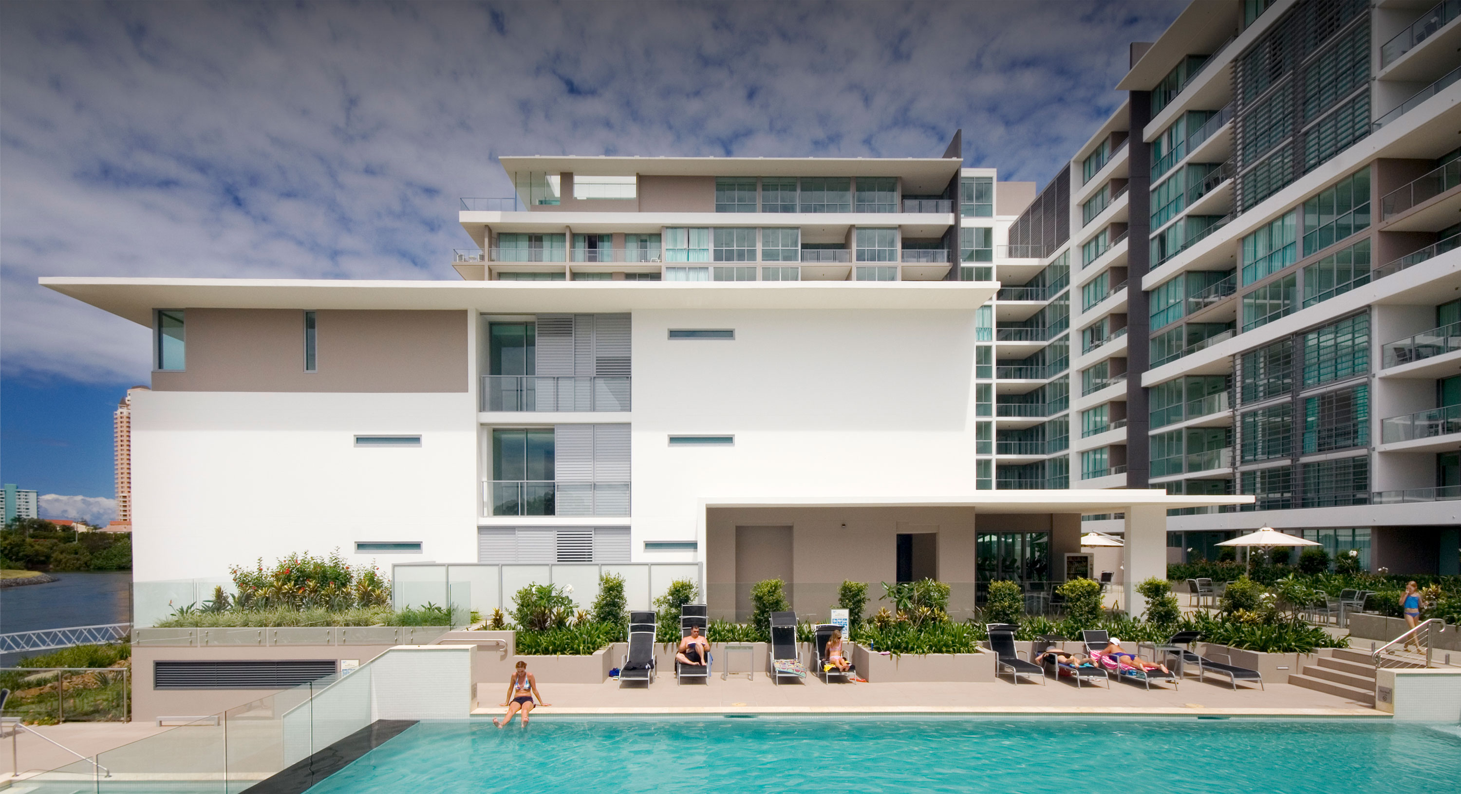 Resort-style pool within the Freshwater Point apartments, with people lounging on deck chairs.