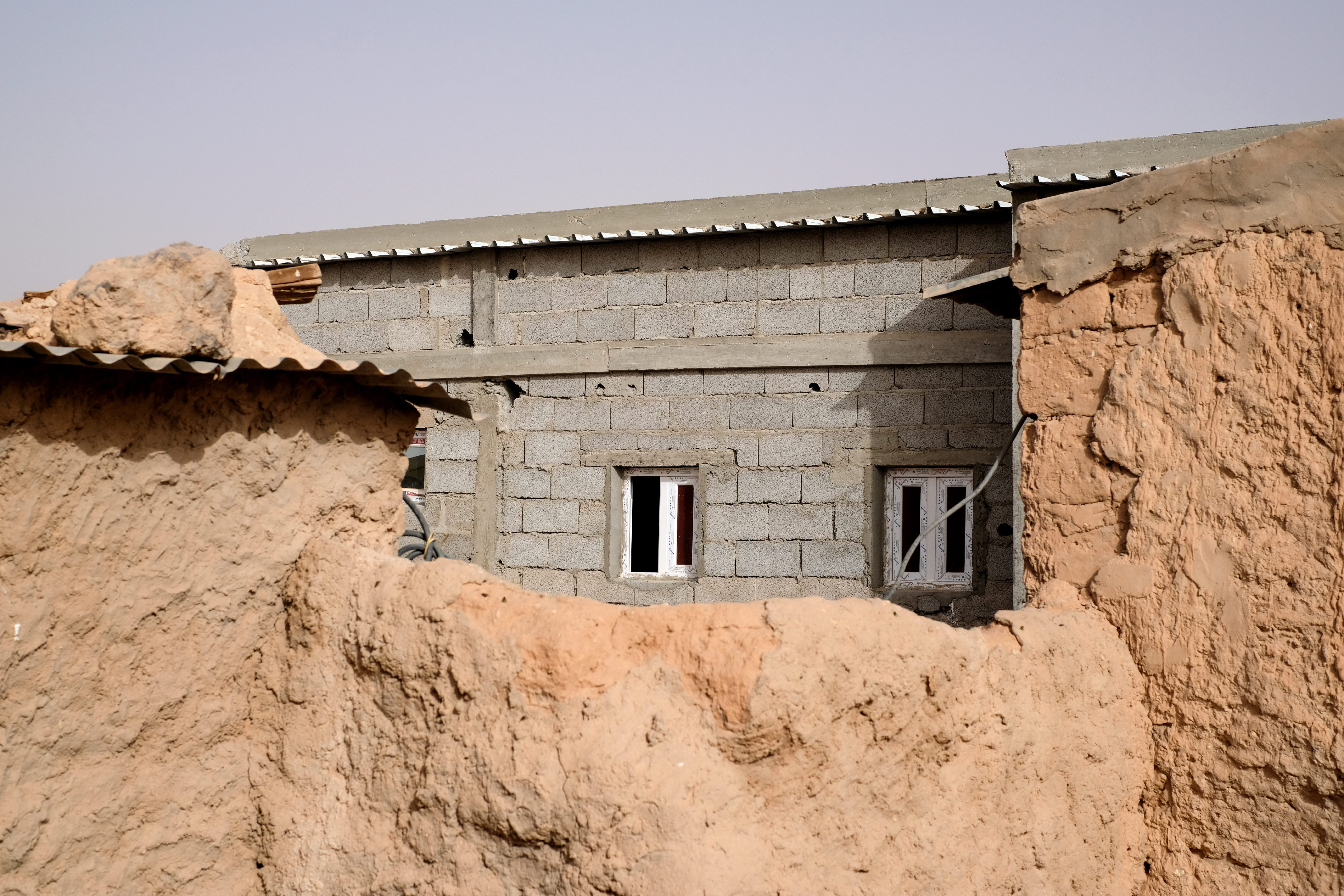 Maison en parpaings construite à côté des restes d'une maison en brique d'adobe détruite par les inondations de 2015 dans le campement de réfugiés sahraouis de Smara, février 2024.