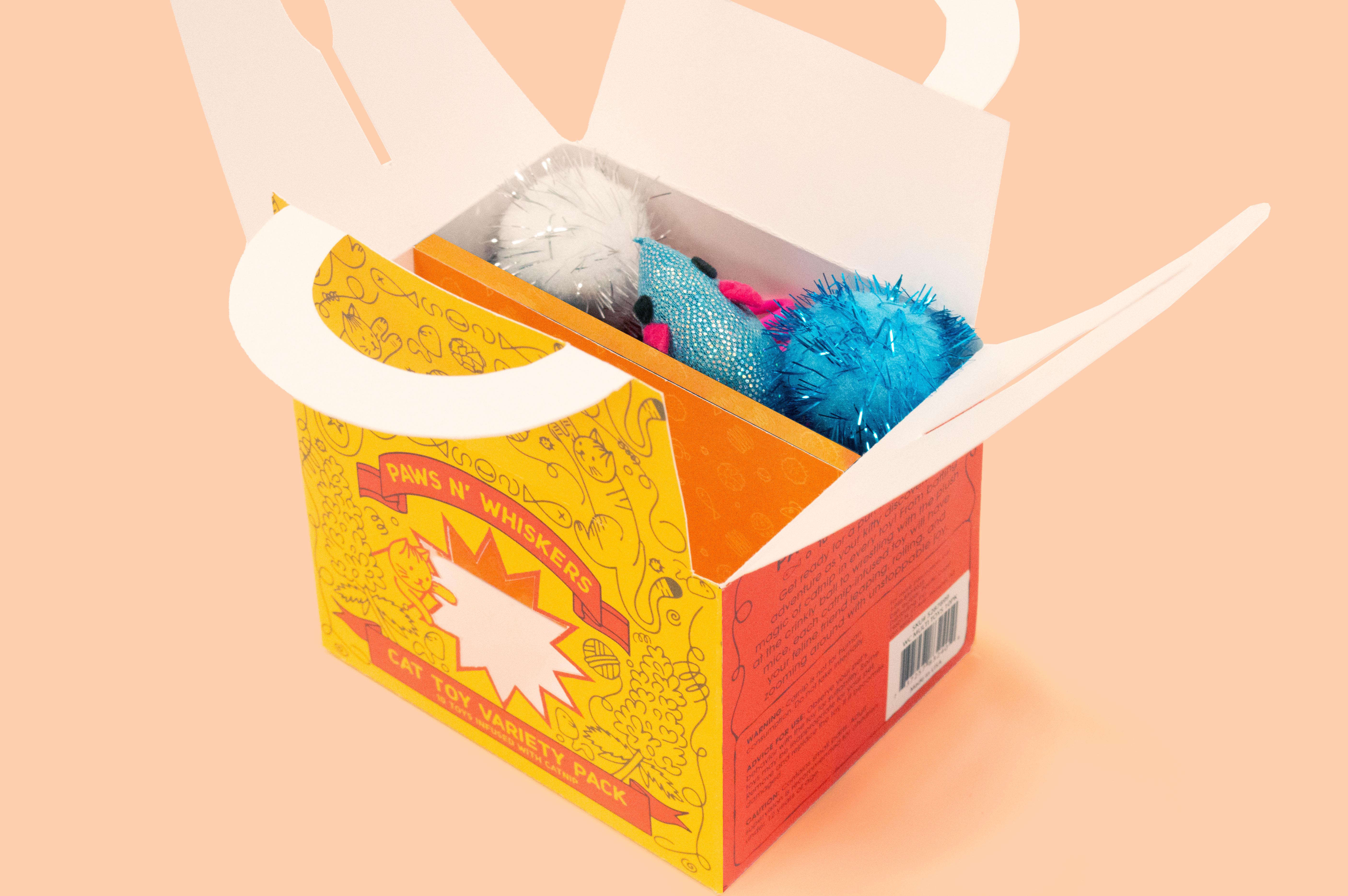 A light orange studio shot featuring an up-top view of an open package that shows the variety of cat toys available for purchase.