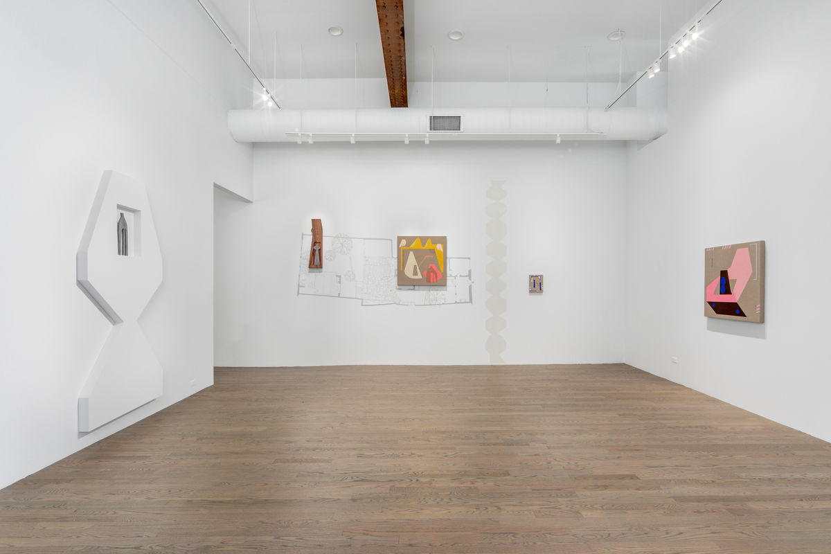 A small white wall gallery space with brown wooden-looking floors, with artworks on the walls to the left, right, and directly in front.