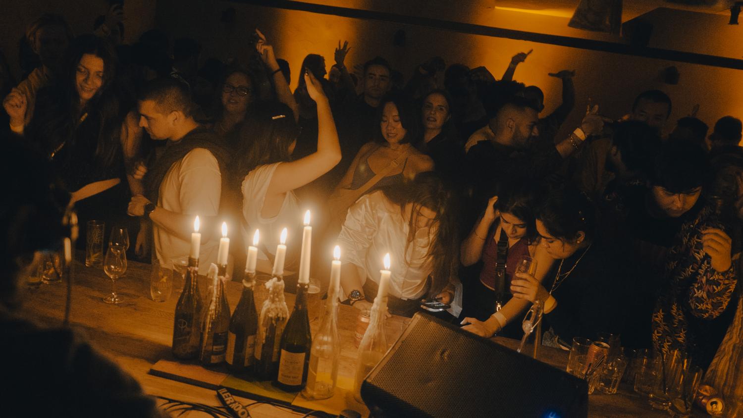 Guests dancing beside candlelit tables during a Paired London evening, blending dining and underground music in an intimate setting.