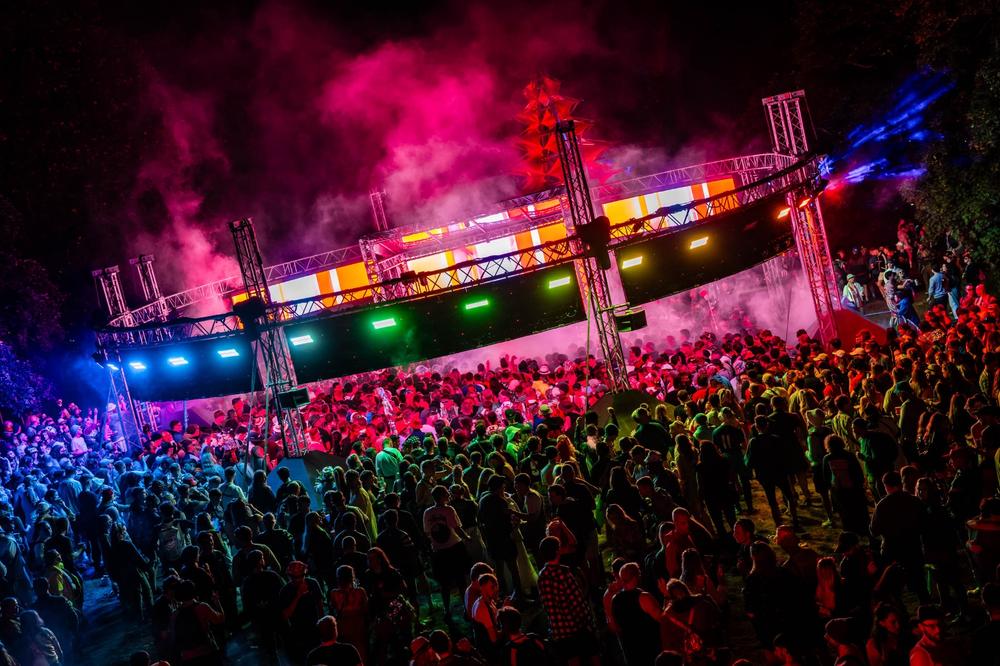 Festival-goers enjoying IMMERSE stage experience under colourful lighting