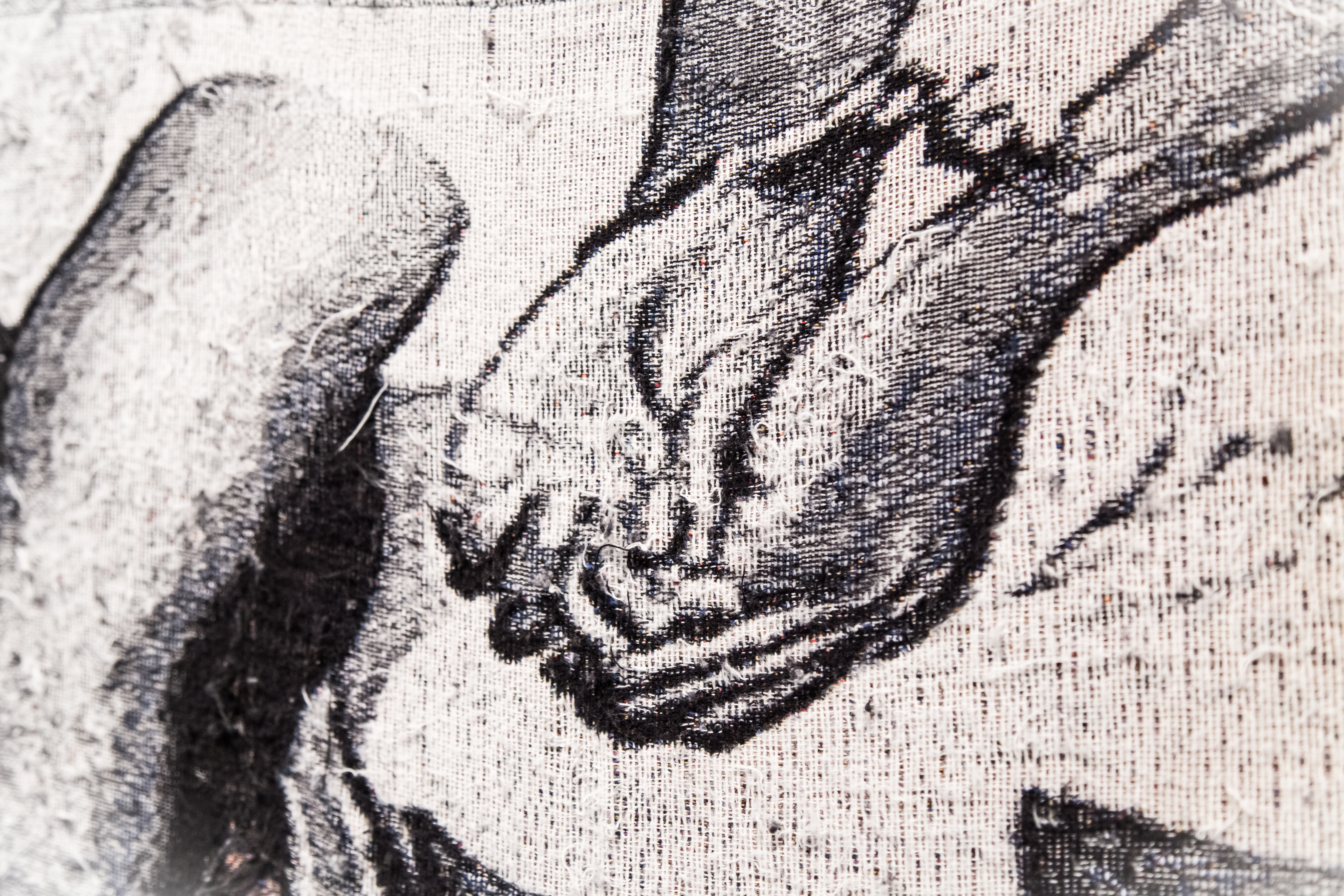 A close up of the tapestry at the top of the page, focusing in on just a pair of Black hands wearing handcuffs. Up close the thread that makes up the larger image is more noticeable. It’s more clear here that the object might be soft to the touch.