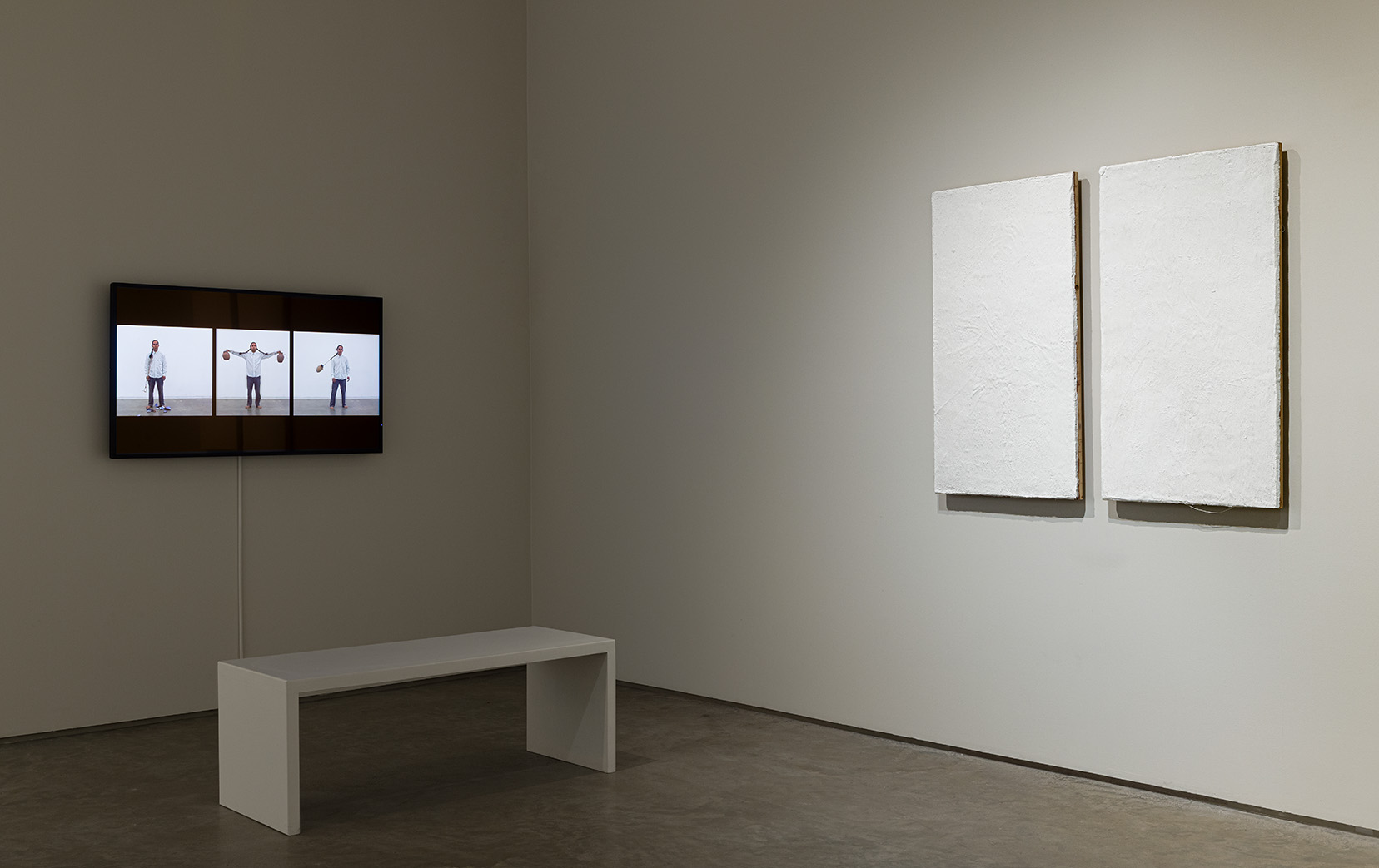 (Left) Armando Guadalupe Cortés, El descanso en el gloria (Rest when I am Dead), 2017. Video documentation of performance, 6 minutes 25 seconds.  (Right) Armando Guadalupe Cortés, Jauiri Kuáti, 2025. Cedar panel, adobe, lime wash, 40 x 21.5 inches each. Photo by Etienne Frossard.
