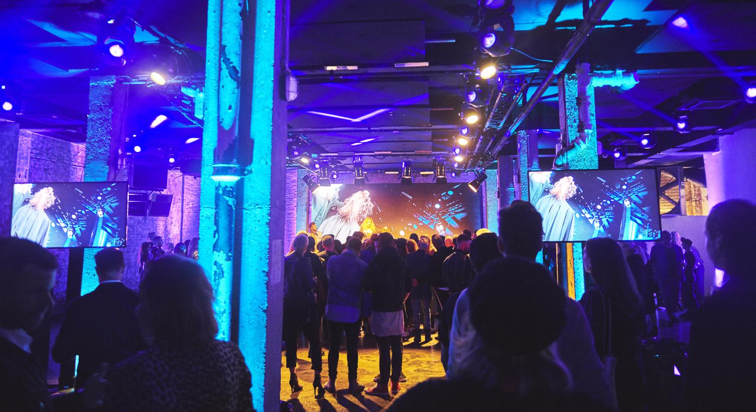 Audience watching live hair demonstration under blue and purple lights at EVO Hair “Don’t Buy This” event.