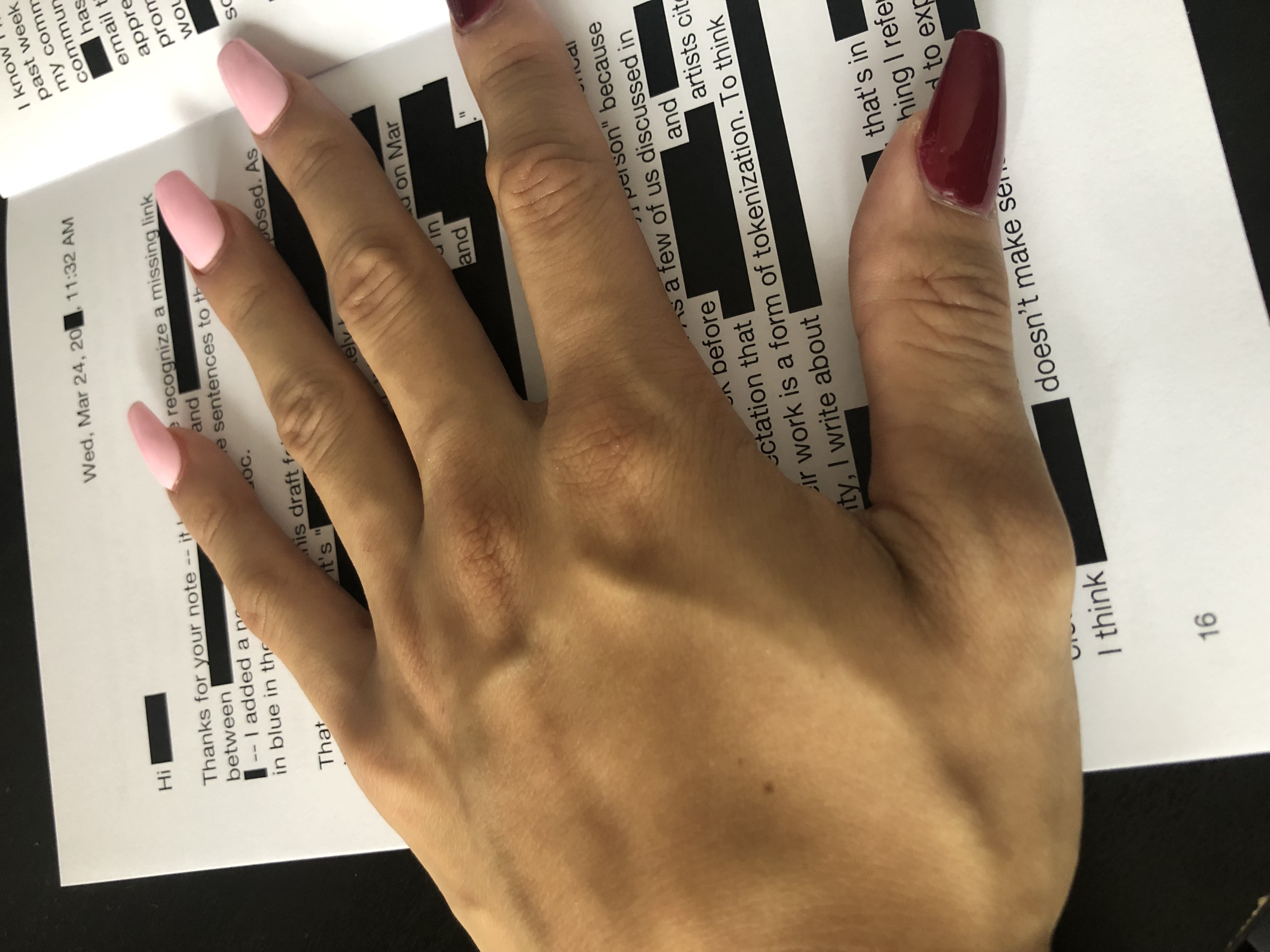 my hand over a proof of "nasty notes" page 16: paragraphs of text with selections blocked out.