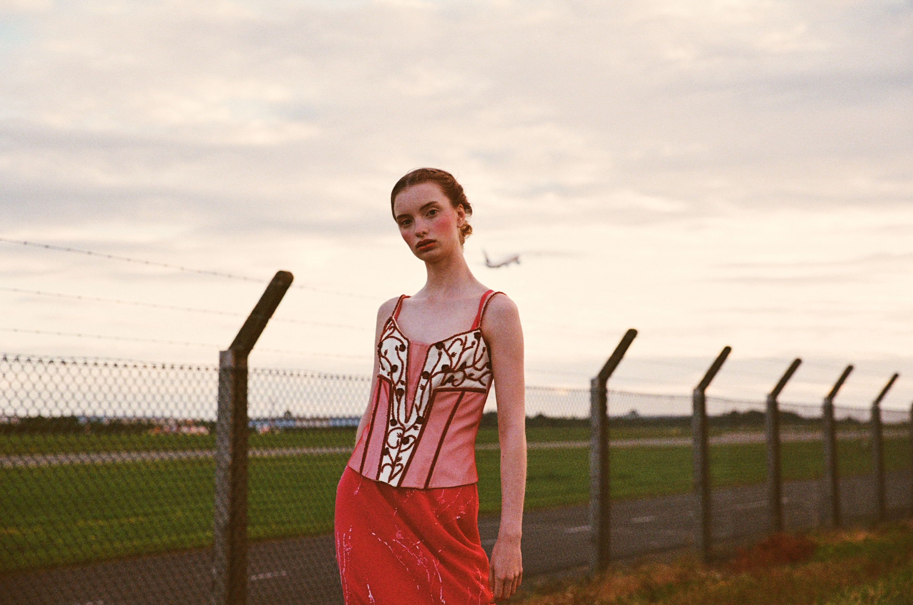 Stylish fashion editorial photoshoot in Dublin, Ireland, featuring a beautiful model in vintage clothes. Captured by a talented photographer for Totally Dublin magazine, this photography showcases the city's unique fashion scene and the beauty of vintage clothing with airplanes in the background. Fashion shoot at an airport.