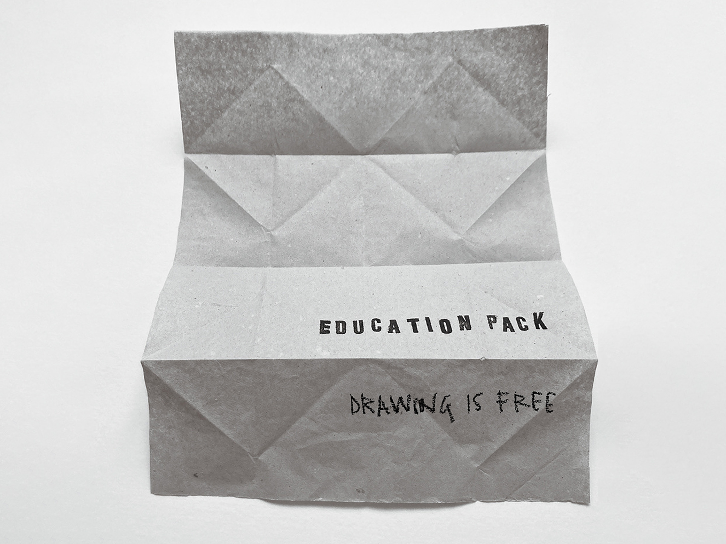 A folded piece of grey paper, printed with Education Pack in block print letters