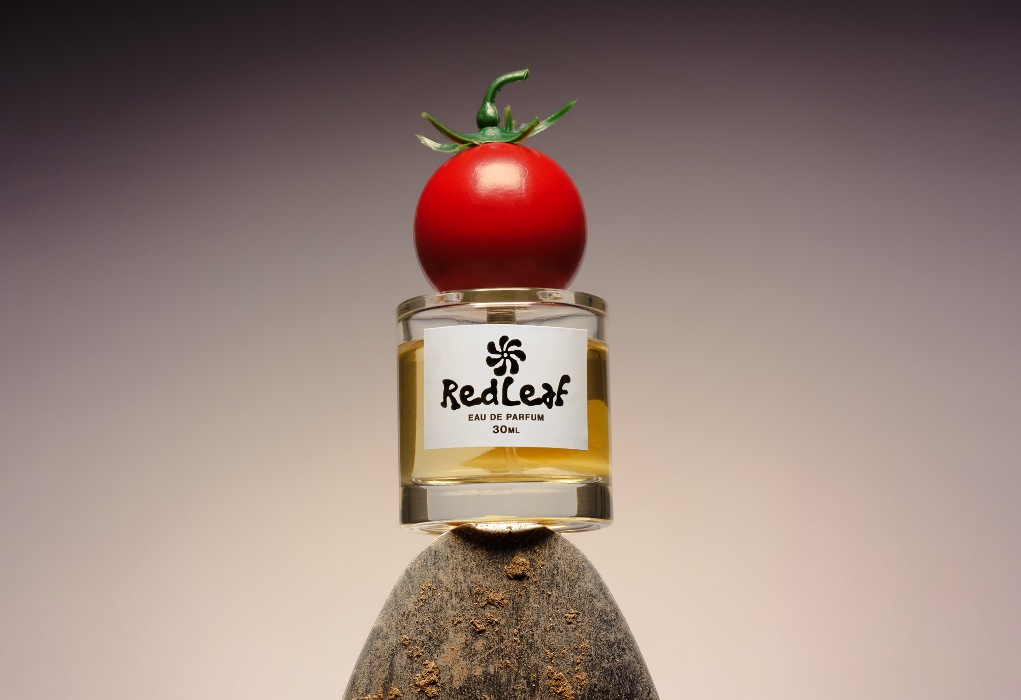 A tomato perfume on top of a hand shovel