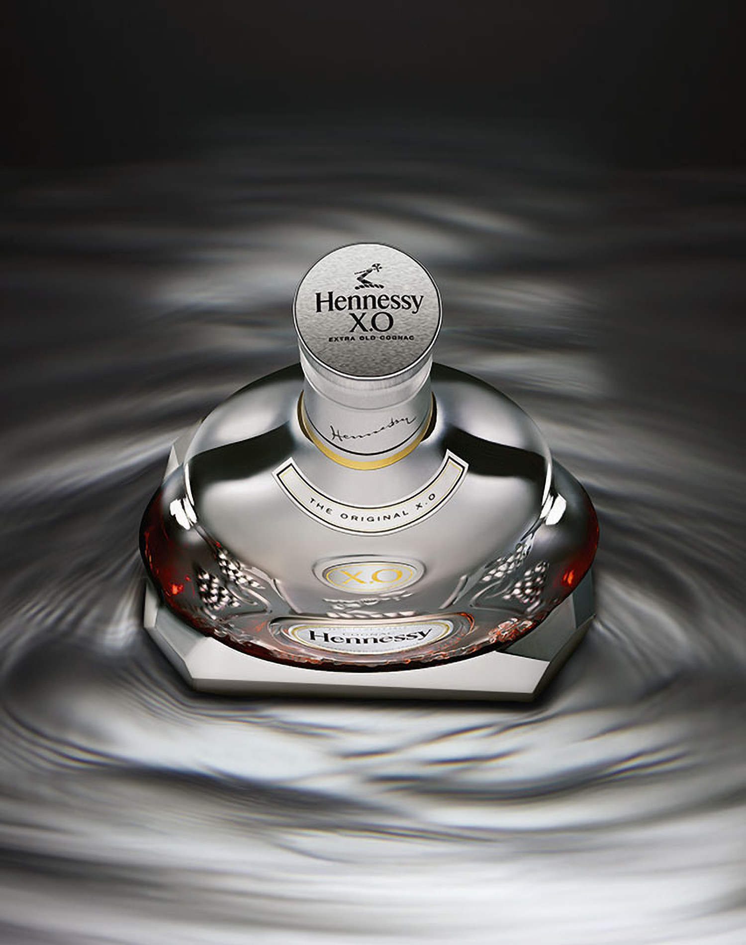 KMA photographer Daniel Schweizer photographs a silver bottle of Hennessy standing on a liquid shimmery silver surface