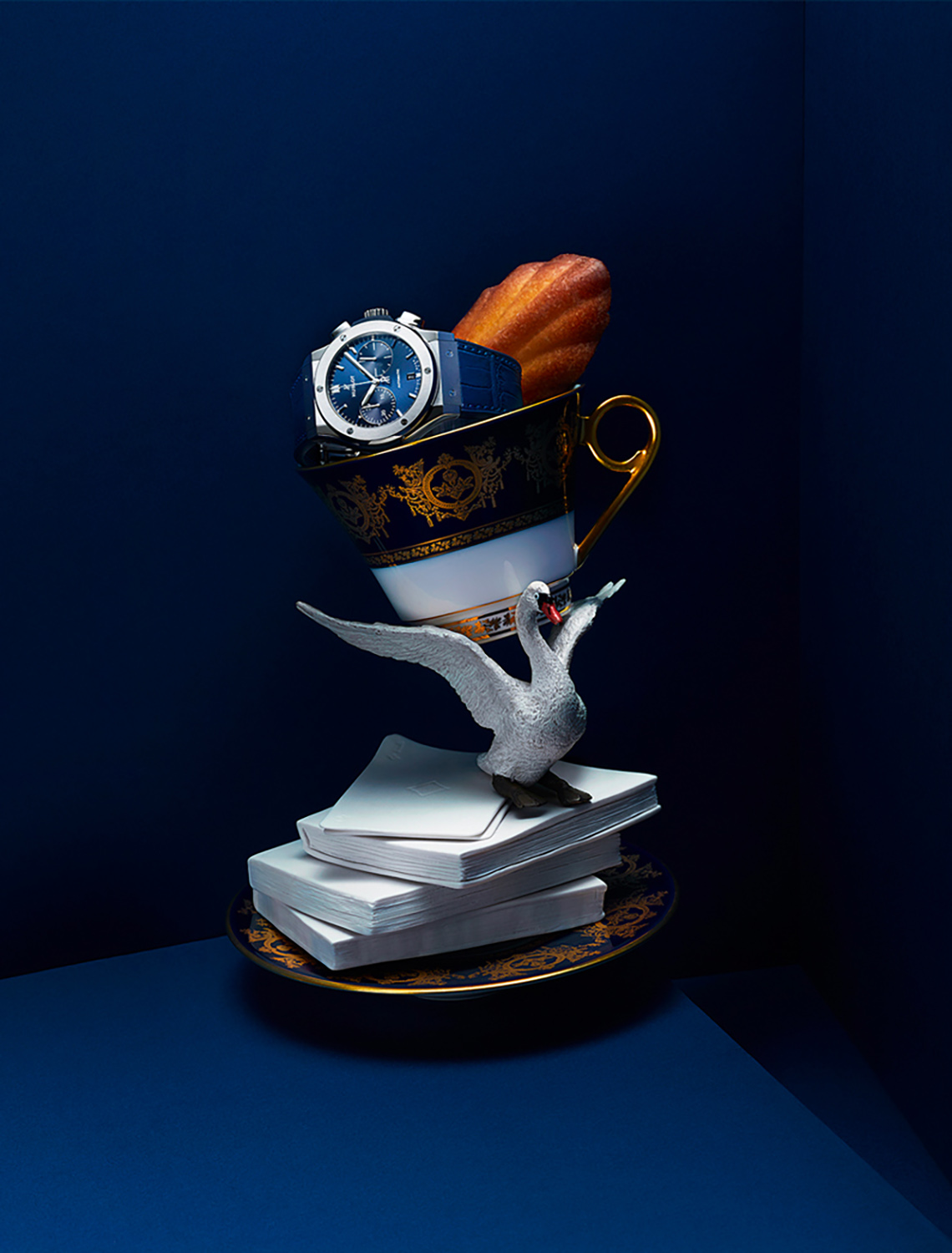 KMA photographer Isabelle Bonjean photographs blue watch a tea cup and a swan against blue background for Ritz Magazine