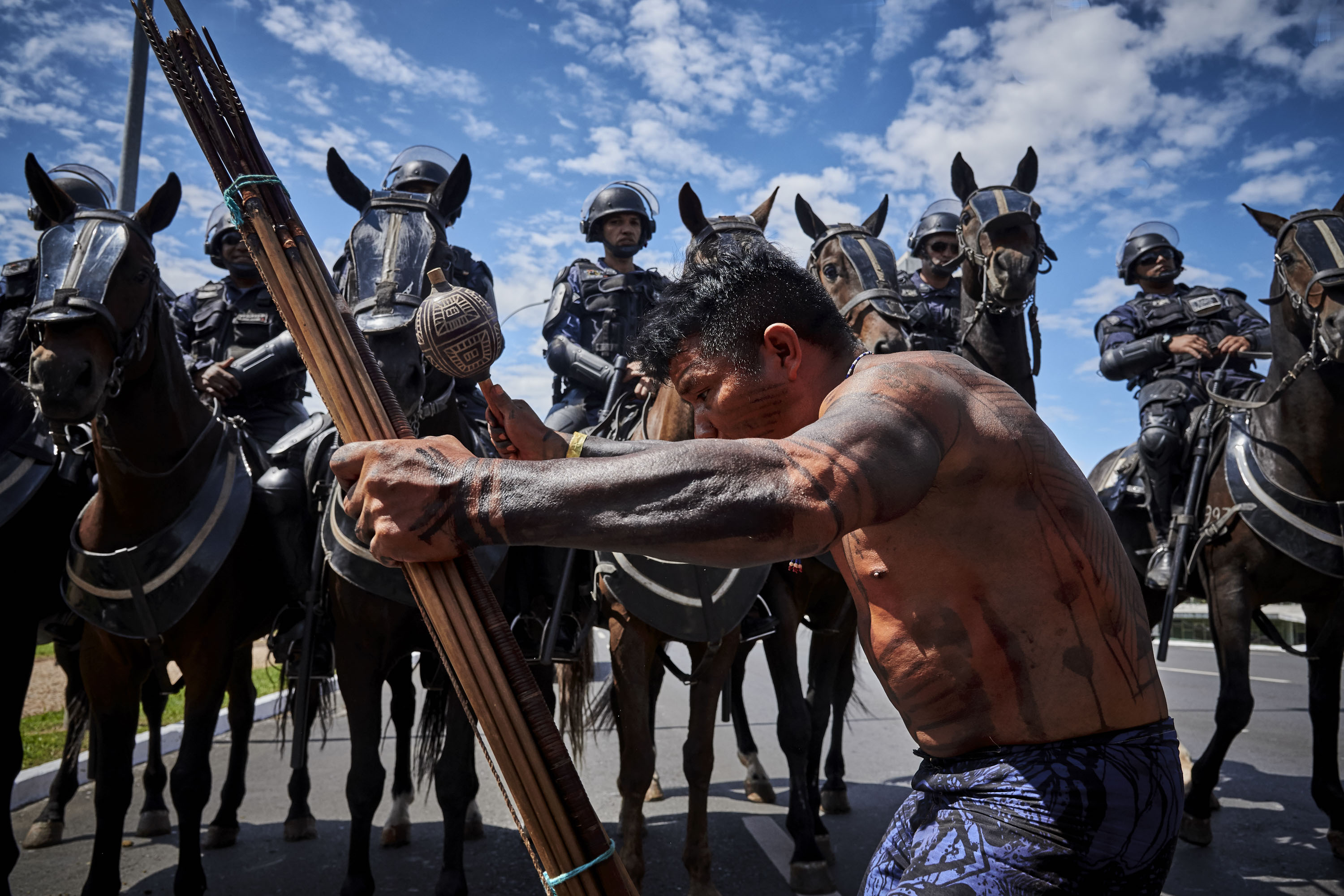 An indigenous man prays and dances in front of the mounting police.