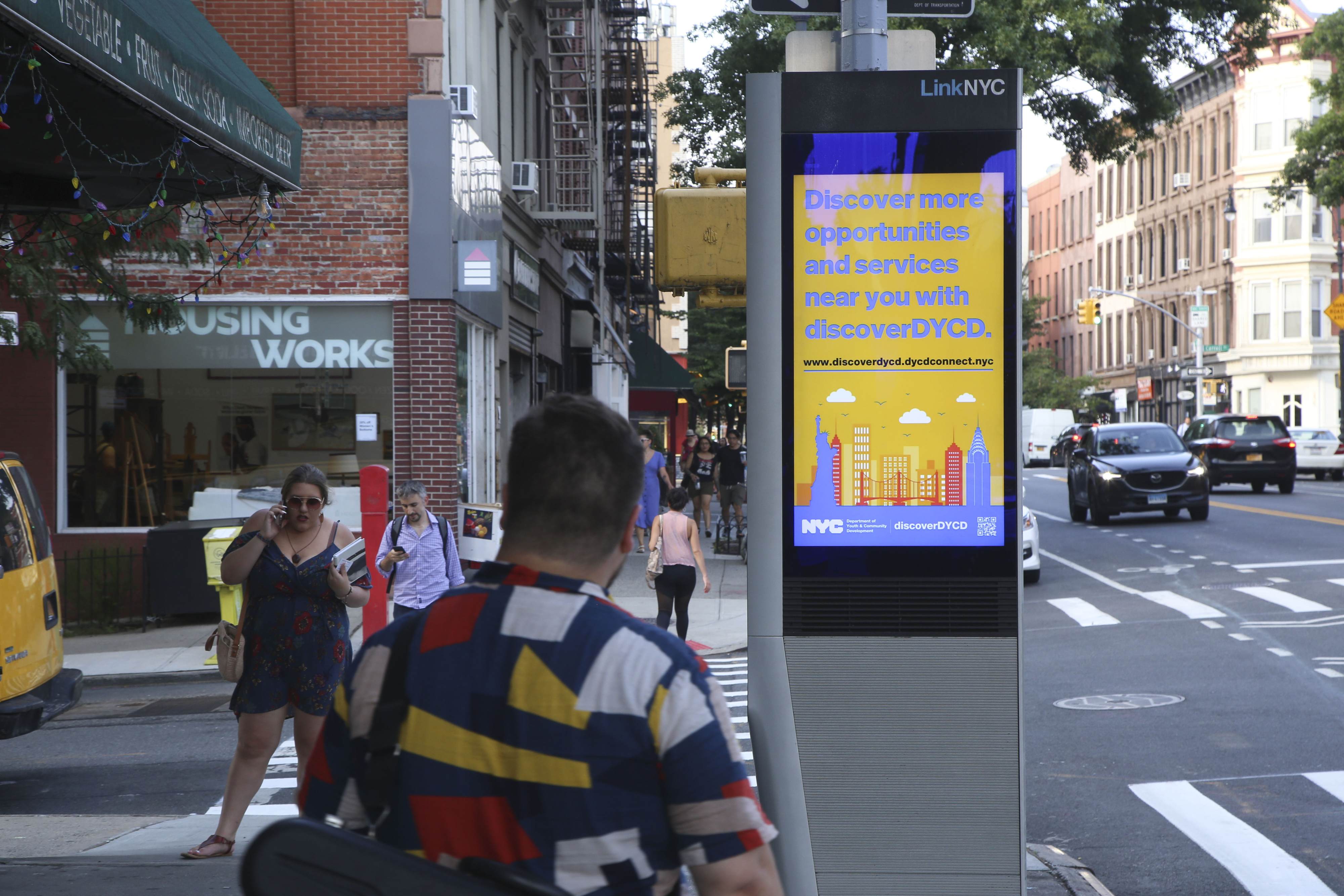 A LinkNYC kiosk displaying the discoverDYCD advertisement which reads, discover more opportunities and services near you with discoverDYCD.