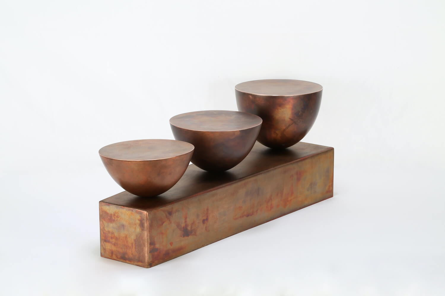 A sculptural form with three metal bowls balancing on a base