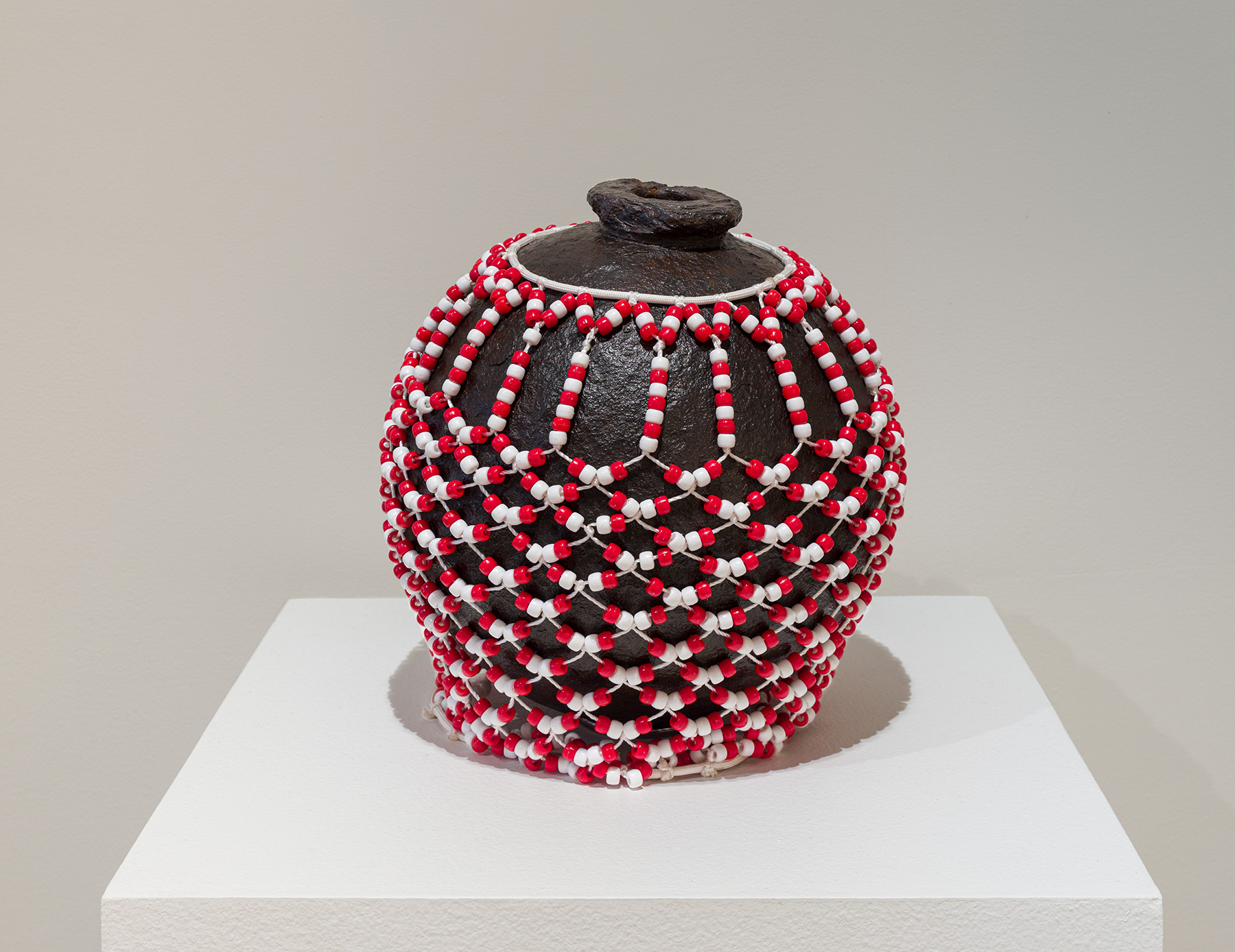 Miguel Luciano, Shekere para Santa Bárbara, 2025. Iron cannonball (c.17th century, Puerto Rico), beads, 12 x 12 x 12 inches. Courtesy of the artist.Photo by Etienne Frossard.