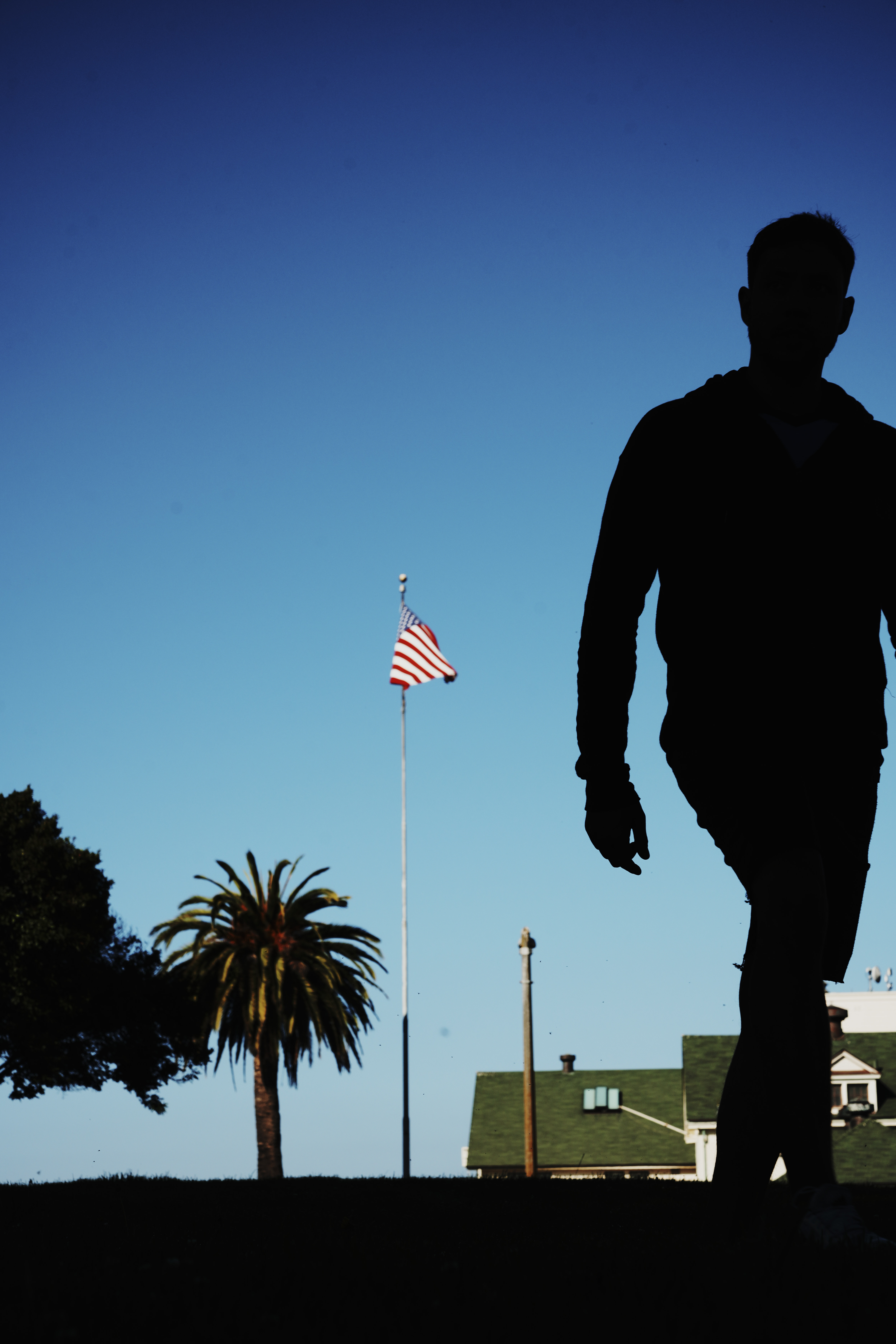Silhouetted against the hopeful blue sky, a lone figure walks by the American flag in the General's Residence located in Northern San Francisco — a symbol of dreams that seems distant in the hard realities of the Tenderloin 25 minutes drive away.