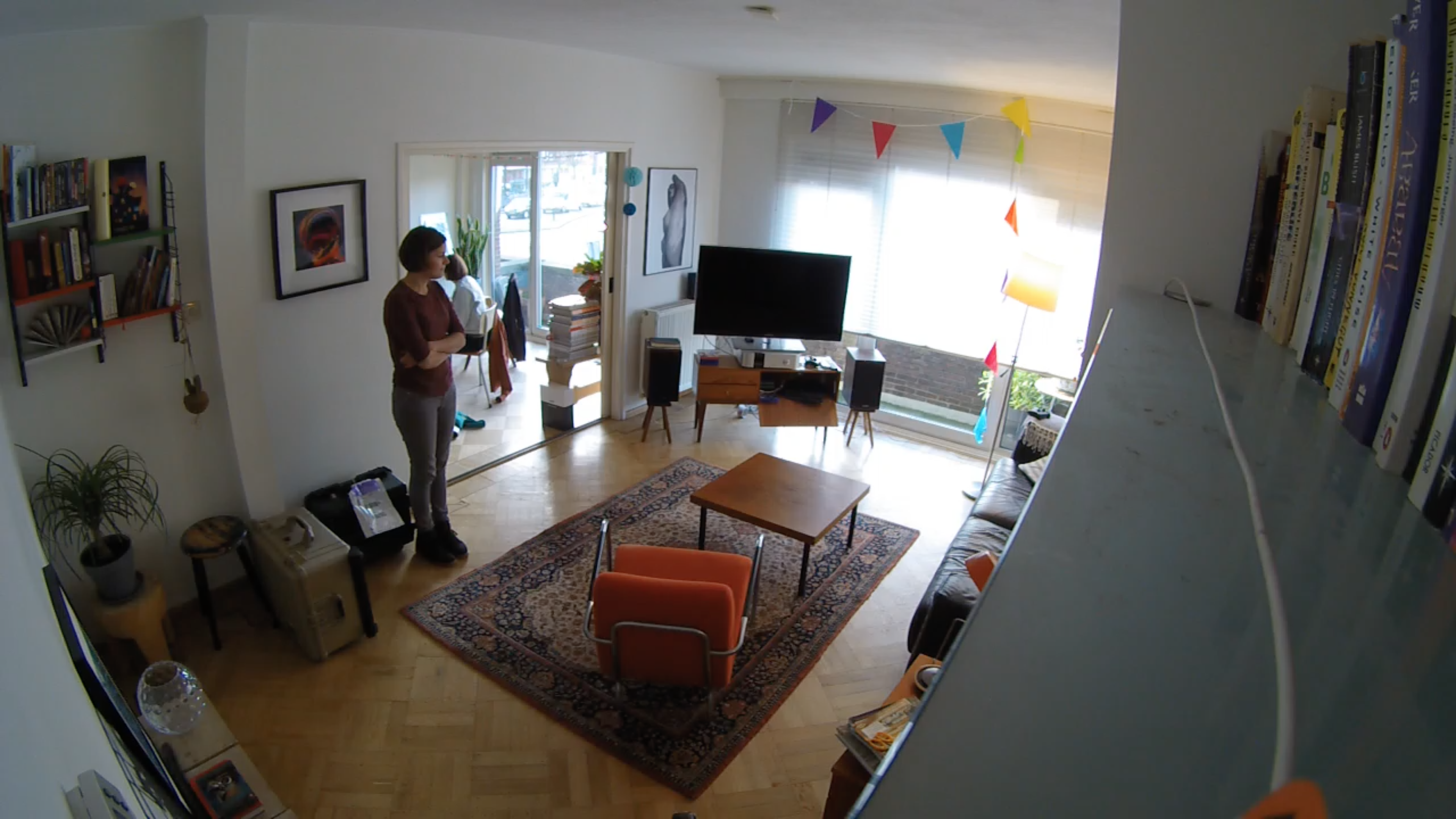 wide angle image of a person in their living room staring at the couch