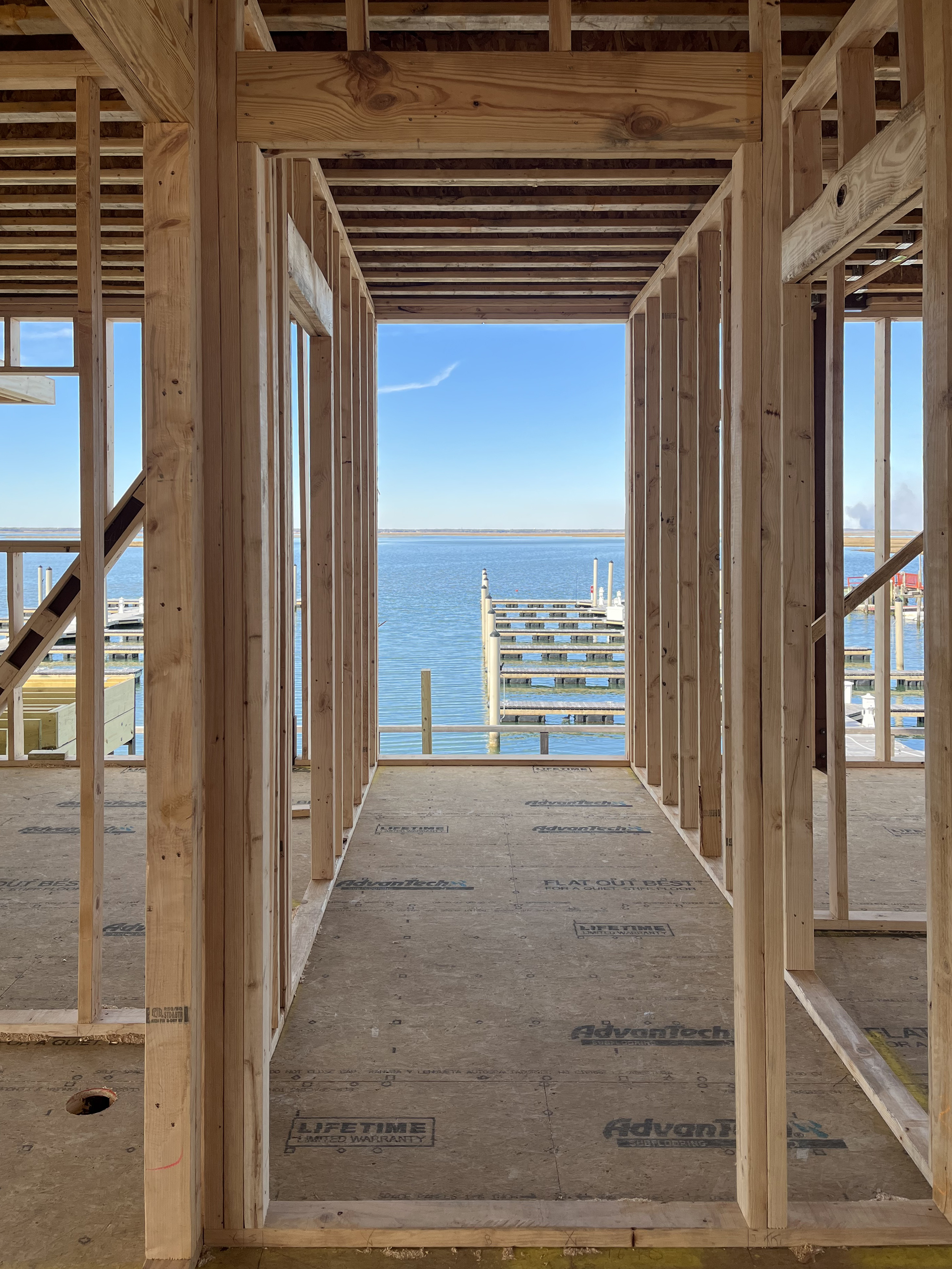 Interior construction photo of the Brigantine Marina Paddle Club showing the wood framing for an interior hallway or passage with a window opening.