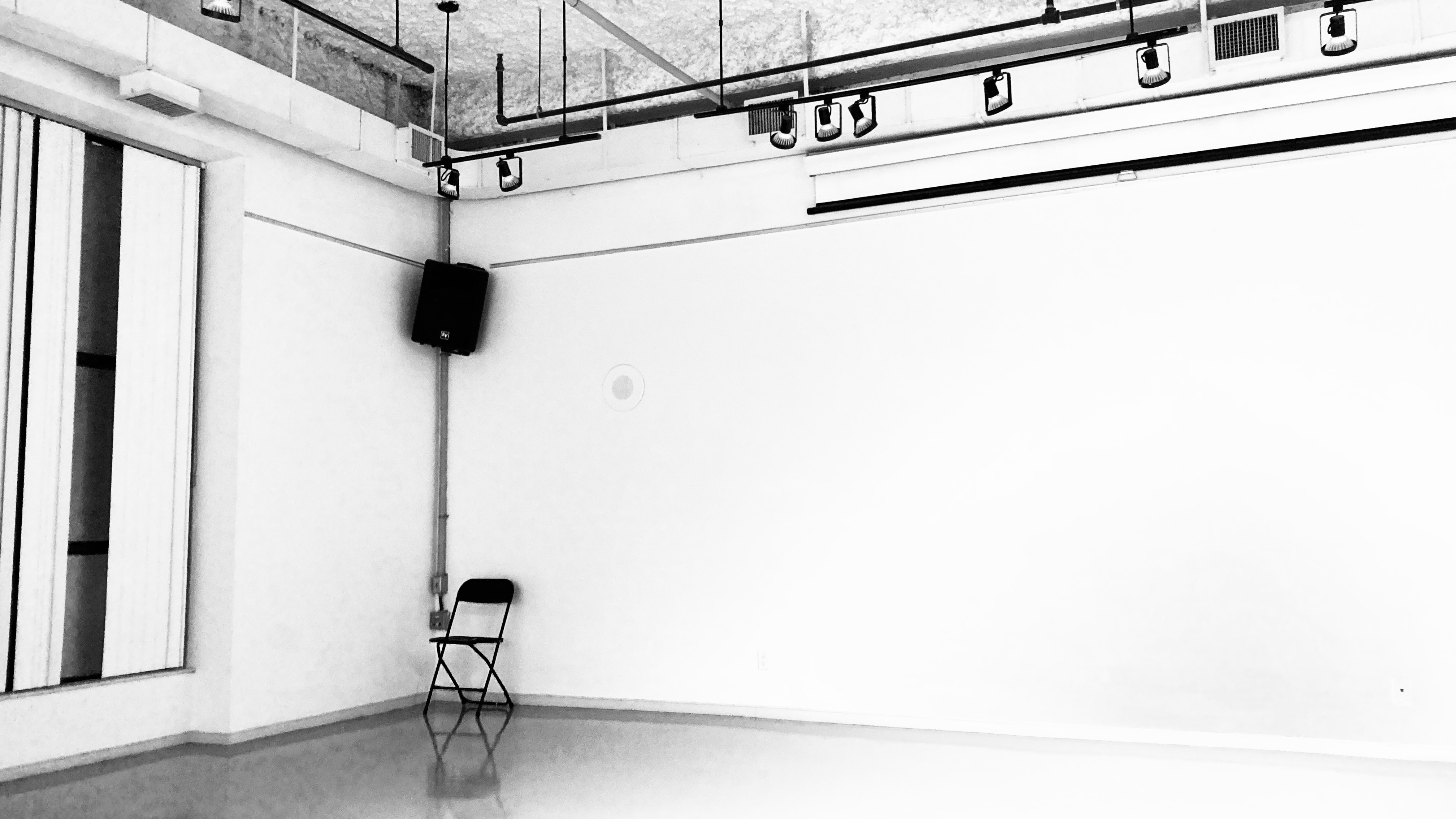A black folding chair in an empty gallery space.