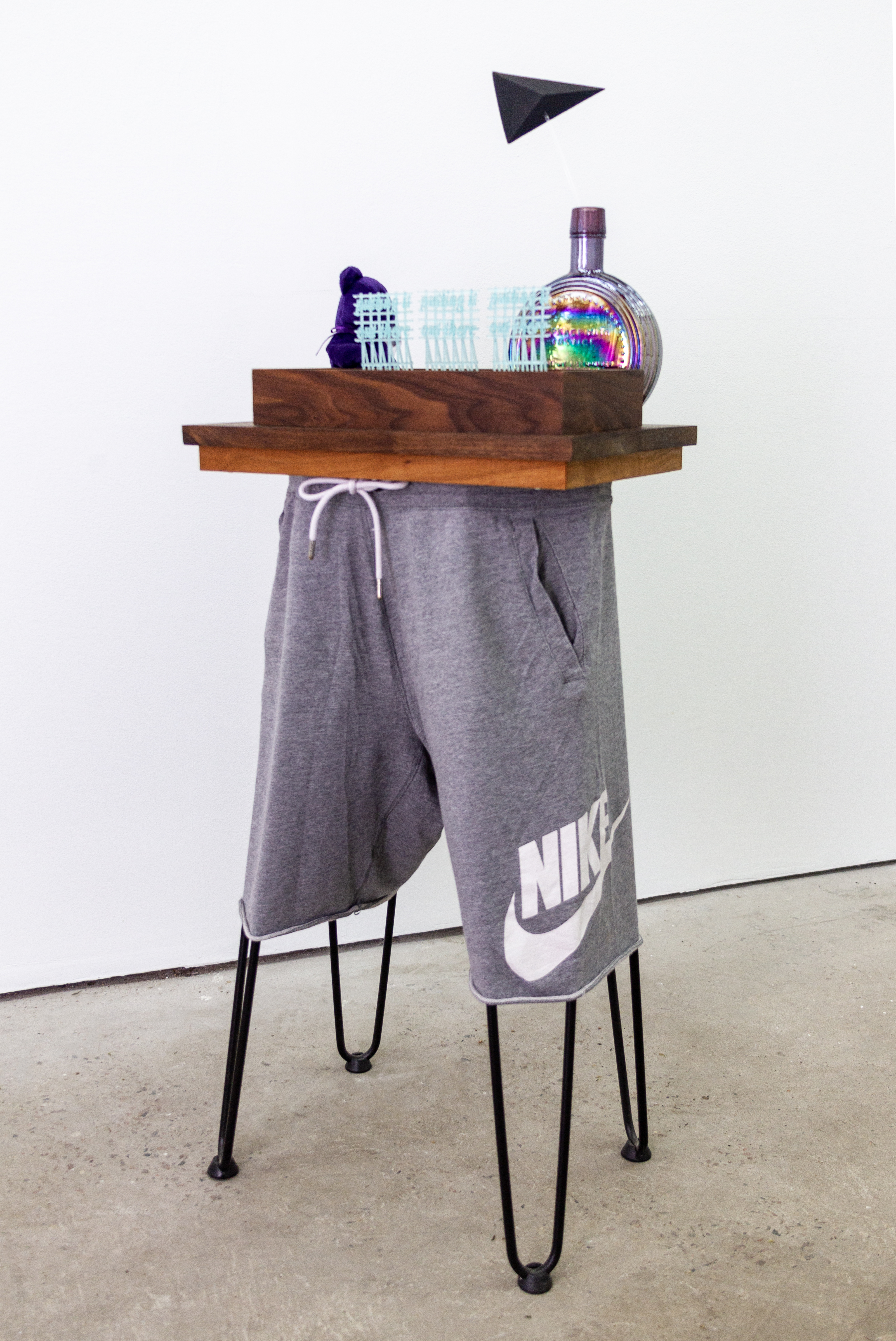 Table (Civic Center), 2023, 44" x 16" x 11". Wood, danish oil, photopolymer resin, polystyrene foam, steel, acrylic plastic, acrylic paint, cotton shorts, glass vase, stuffed animal, faux grass, faux dirt, pva adhesive, hardware