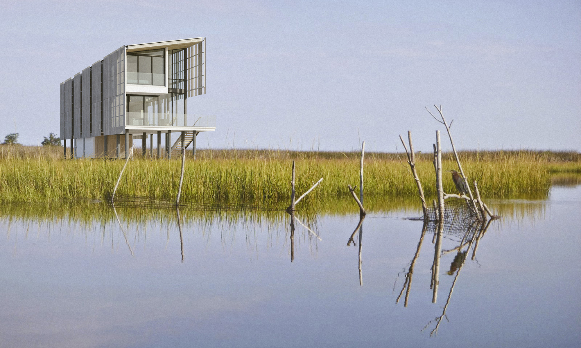 The Salt Box residence viewed from the Barnegat Bay marshes, highlighting the elevated, rectilinear form and the vertical Atlantic White Cedar rain screen against the expansive water and low-lying vegetation.