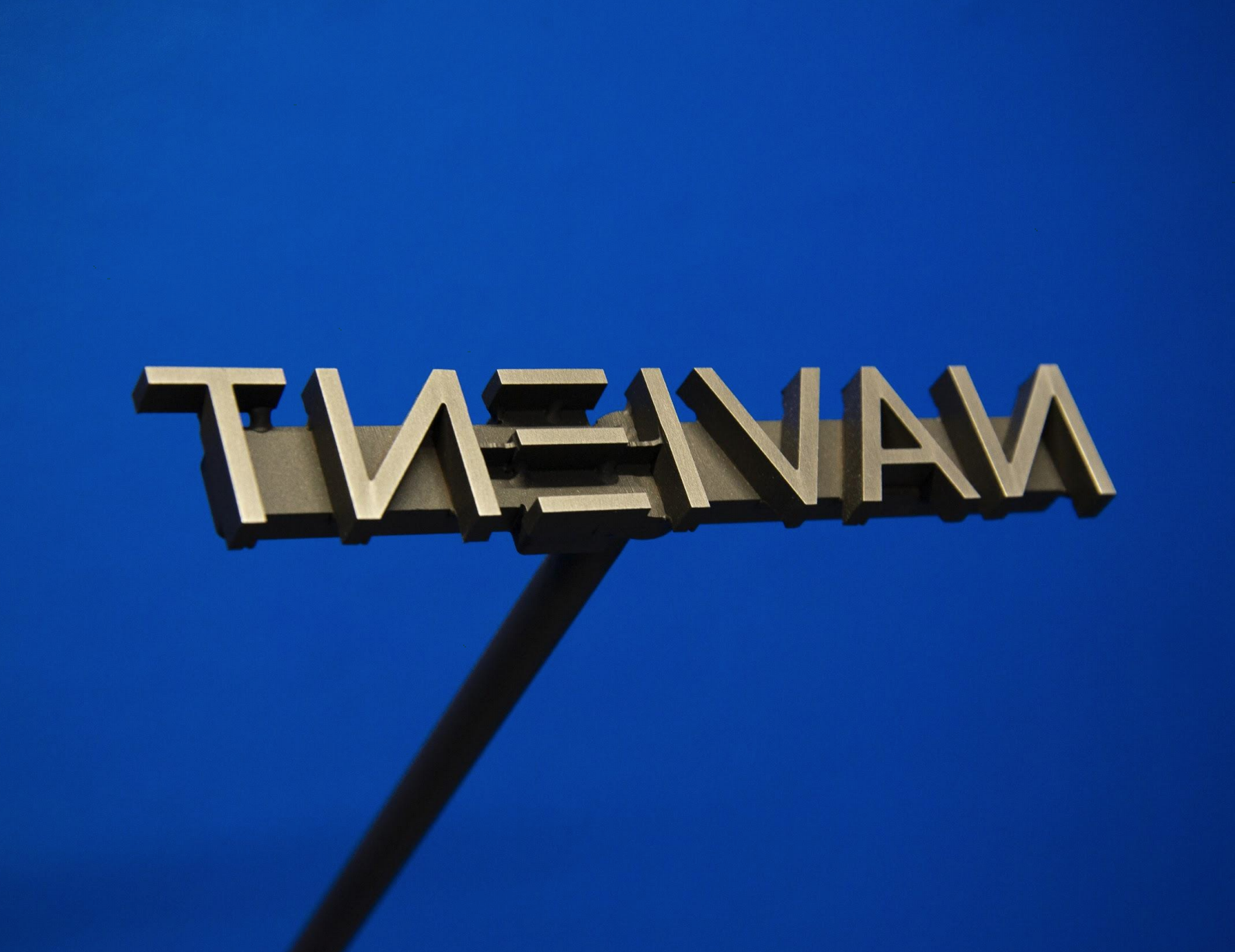 Camilo Godoy, Debtor (Navient), 2019. Stainless steel and blue wall, 3 × 5 × 34 inches.