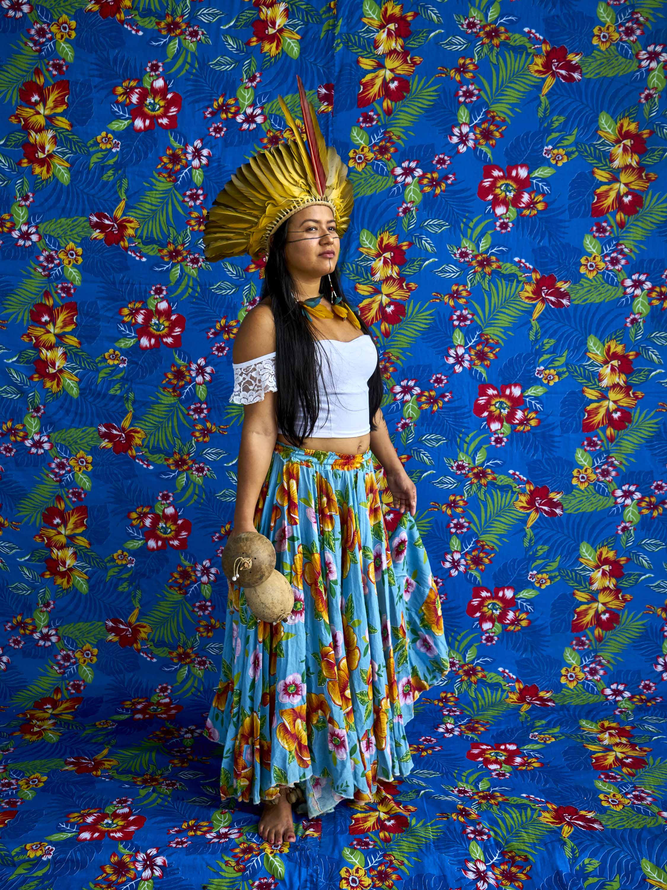 Adelina Borarí, a member of the Suraras do Tapajós Carimbo group, poses for a portrait with her colorful feather headdress and her coconut-made rattles.