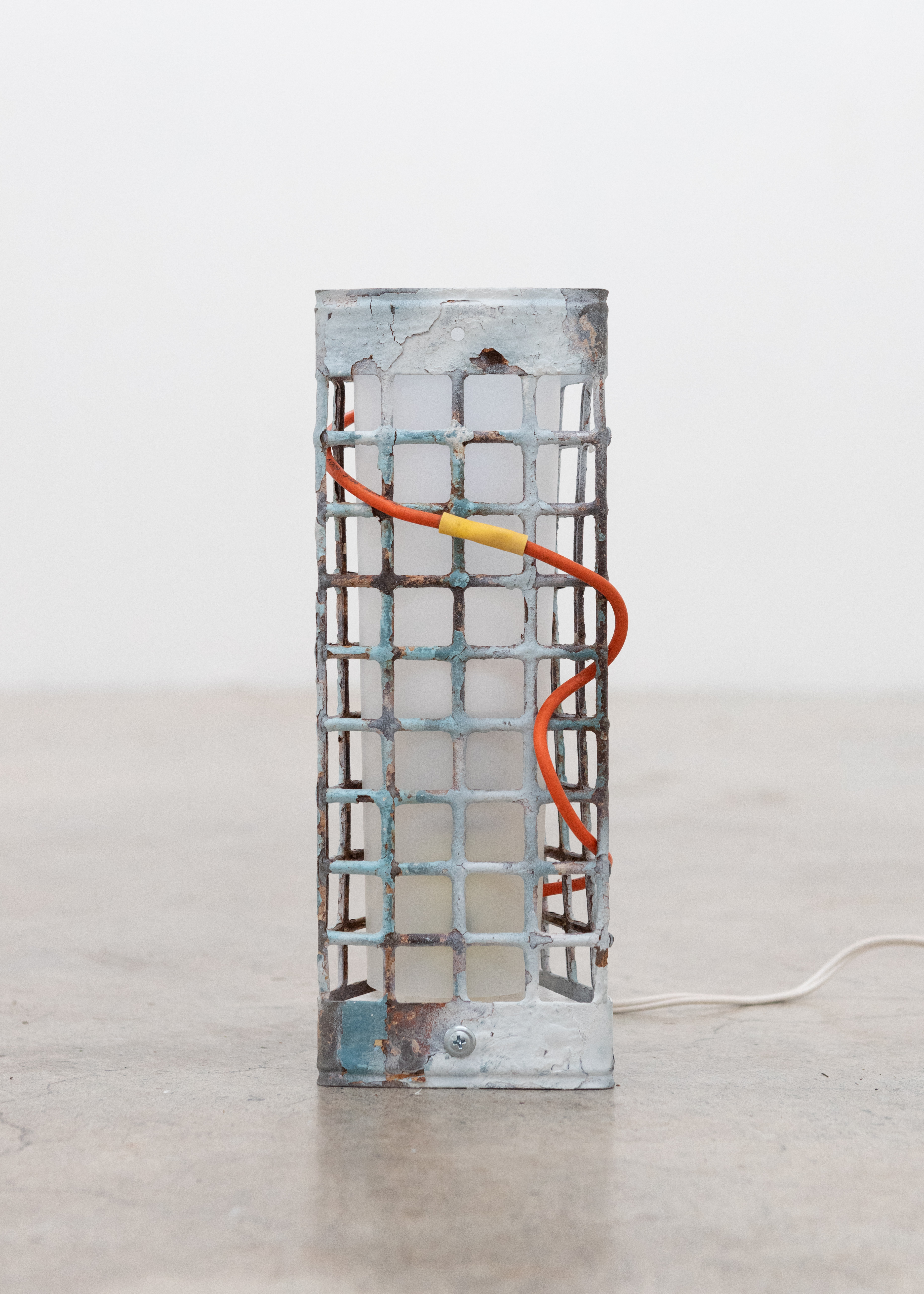 Rusty Lamp, 2025. Reclaimed metal and wire, vinyl sheet, light bulb, 3 x 5 x 11 in.