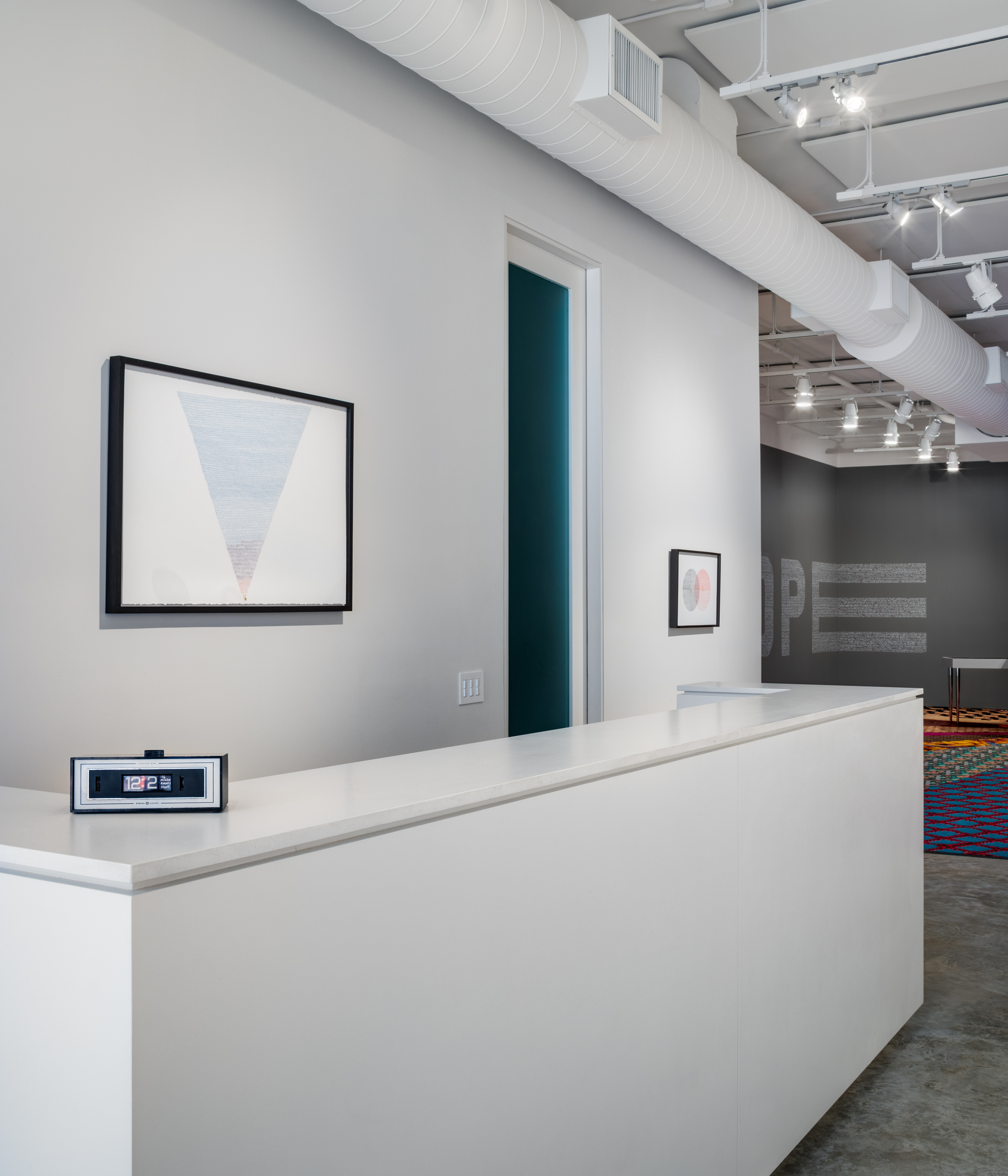 Installation shot, Statistics of Hope  by Ghost of a Dream and Jennifer Dalton. From left to right: Internet Minutes, 2018. Acrylic on paper in vintage digital clock, 3 x 7 1/2 x 3 inches. Ways You Can Die that are More Likely than Being Killed by a "Refugee Terrorist", 2018. Ink on paper, 28 1/2 x 41 1/2 inches. One Minute of Marriages and Divorces, 2018. Ink and clockworks on paper, 16 1/2 x 24 1/4 inches. Statistics of HOPE, 2018. Paint pen on wall, 50 x 198 x 49 inches.Where You Stand, 2018. Salvaged casino carpet, 21 x 36 feet. (Credit: Rafael Gamo)