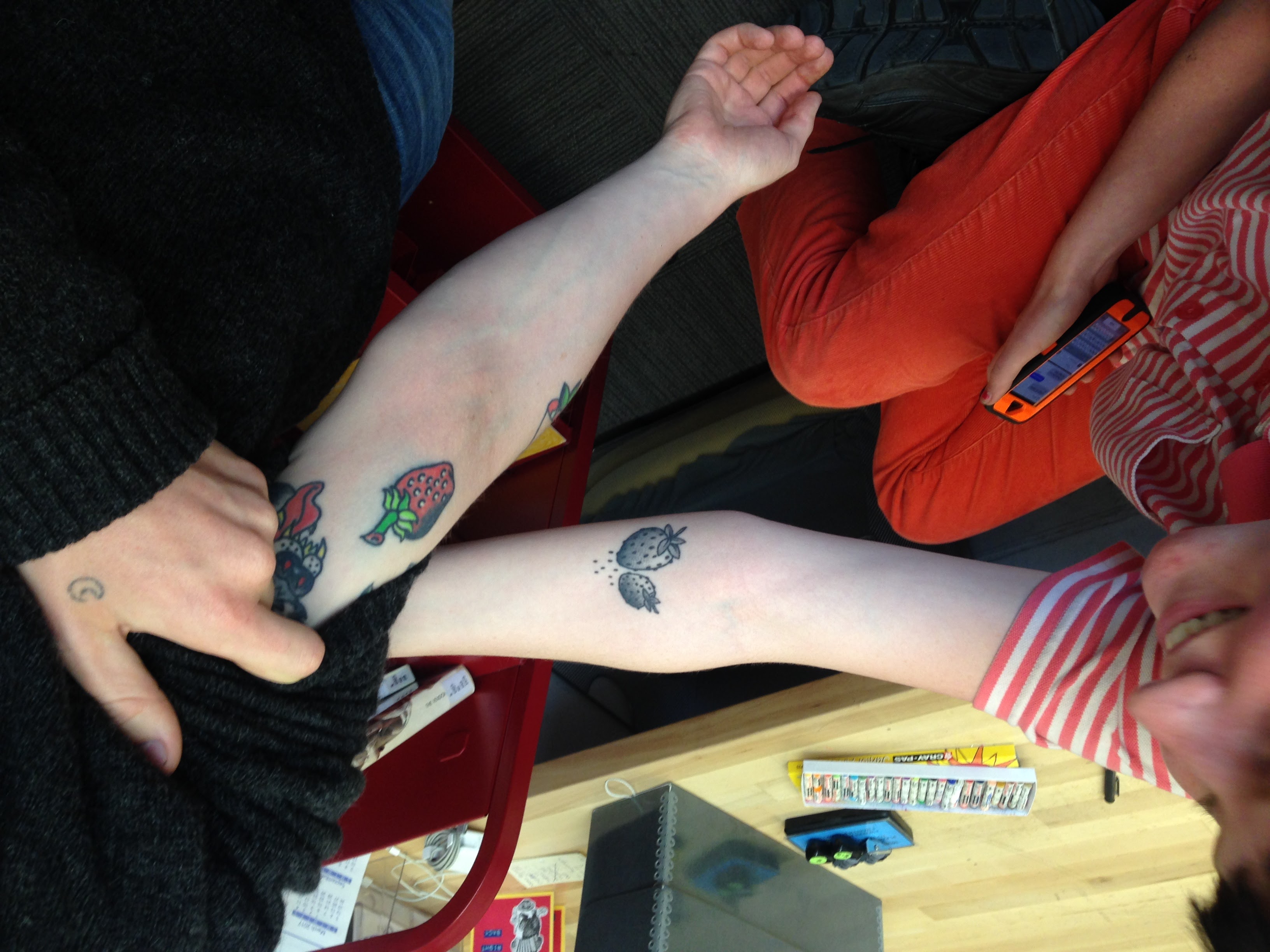 SFAI student library workers Blythe Feeney and Max Blue check out each other’s strawberry forearm tattoos while checking out books at the circulation desk. In the last thirty years tattoos have become commonplace with SFAI students and faculty.