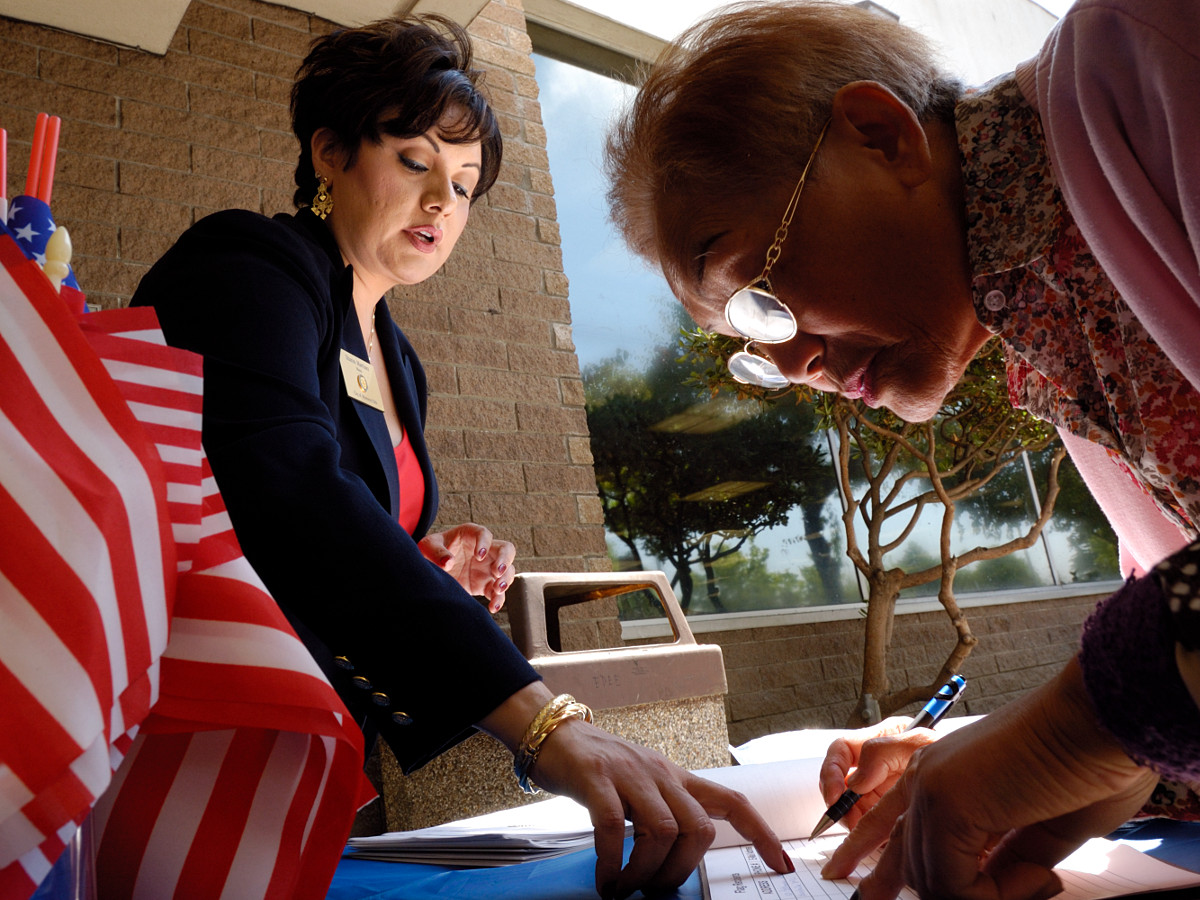 Sharon Martinez, left, mayor of Monterey Park, California, shows a new voter where to sign for a free flag during a voter registration drive at the city public library on July 1, 2004. Ho-Yen Tsang for The San Gabriel Valley Tribune