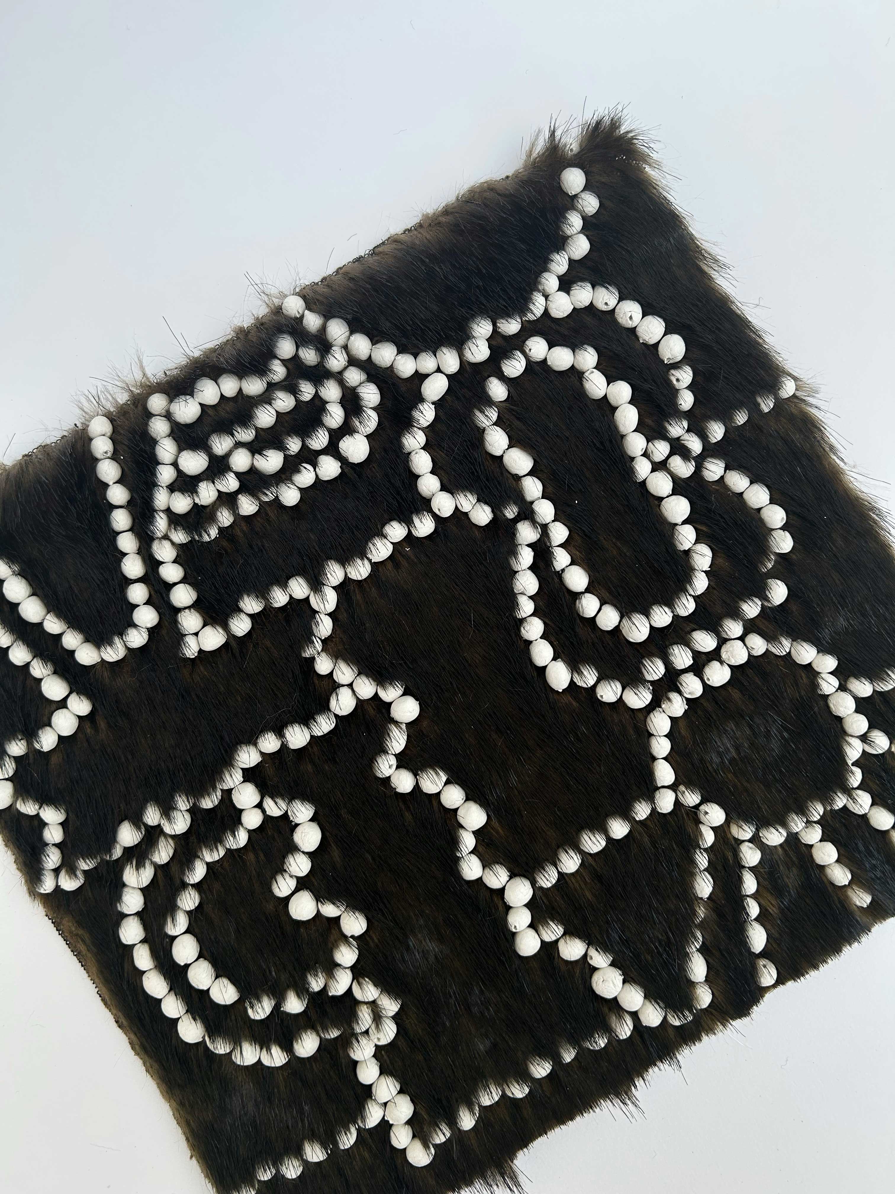 RECHERCHES ET PROTOTYPES. PERLES EN ARGILE AUTO-DURCISSANTE BRODÉES SUR DE LA FAUSSE FOURRURE.