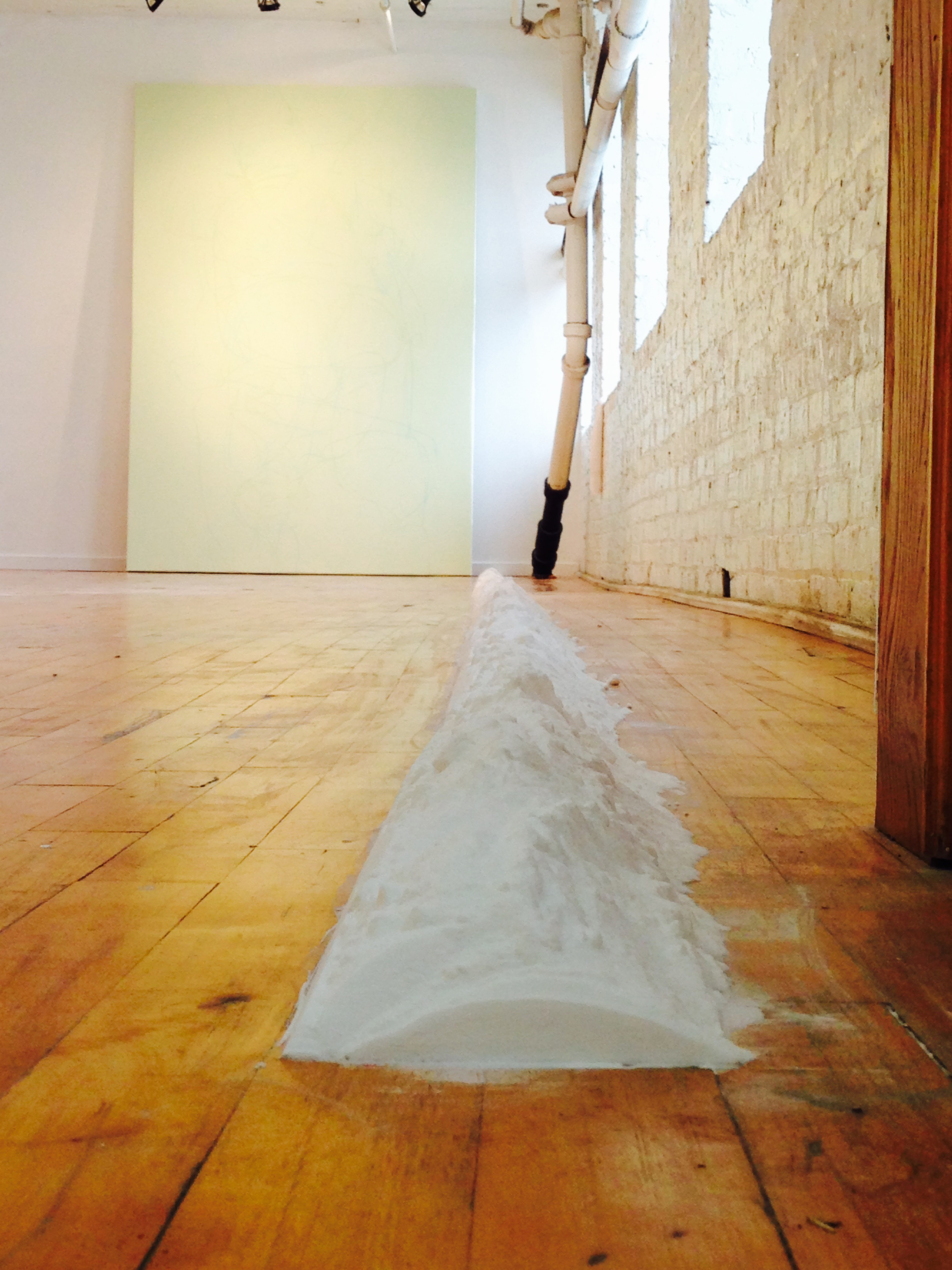 1/3 — A WALL OF FLOUR.  The site-responsive installation A Wall of Flour. 6.12.15 was created for the exhibition Body Mass Index, curated by George William Price.  150 lbs. sodium bicarbonate, floor, dimensions variable, approximately 6" x 540", the distance between work and wall/windows equal to reach of the artist's/activator's arms, 2015.