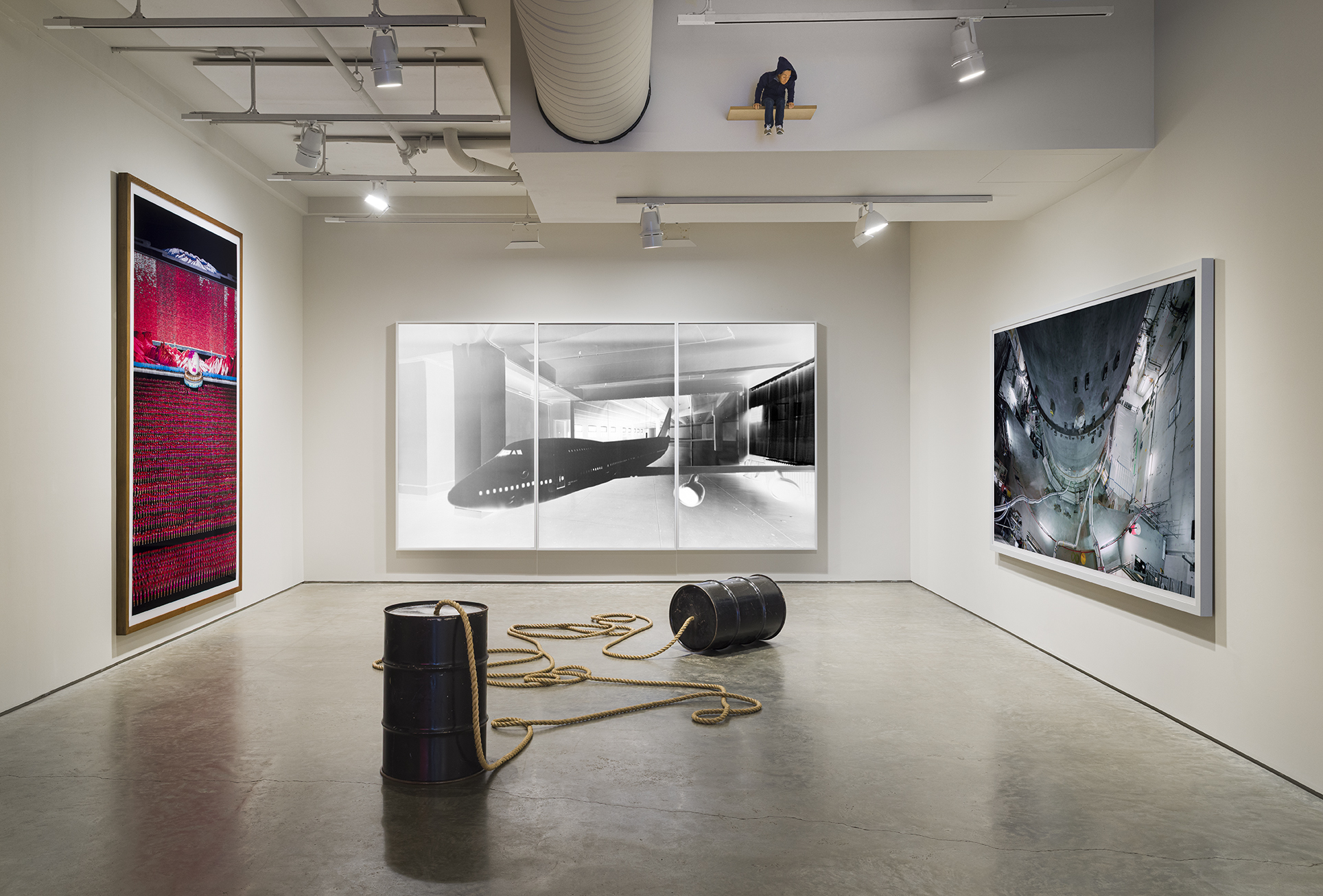 From left to right: Andreas Gursky, Pyongyang IV, 2007. C-print, 82 5/16 x 101 15/16 inches; Vera Lutter, Studio, XXX: June 29 - July 18, 2006, 2006. Unique silver gelatin print, 91 1/2 x 168 inches; Thomas Struth, Reactor Pressure Vessel Phase Out, AKW Würgassen, Beverungen, Germany, 2009. C-print, 69 1/4 x 122 1/4 inches. Center: Christian Marclay, Dialogue of the Giants, 1998. Metal drums and rope, each Drum: 28 3/4 x 18 1/2 inches. Photo by Etienne Frossard.