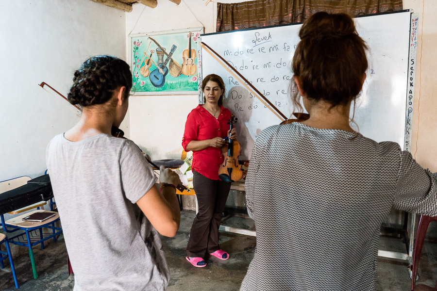 Camp de Maxmur, Irak. Evidar et Mezgin répètent sous l'attentif de Medya. Originaire du Rojava, Medya a rejoint la guerilla où elle s'est illustrée par ses talents musicaux. Le PKK l'a donc chargée d'enseigner la musique aux jeunes de Maxmur. Il y est en poste depuis 4 ans. Pour le PKK, la culture kurde, et plus généralement l'éducation artistique est une composante importante de leur idéologie, qu'ils appellent "la révolution des arts".