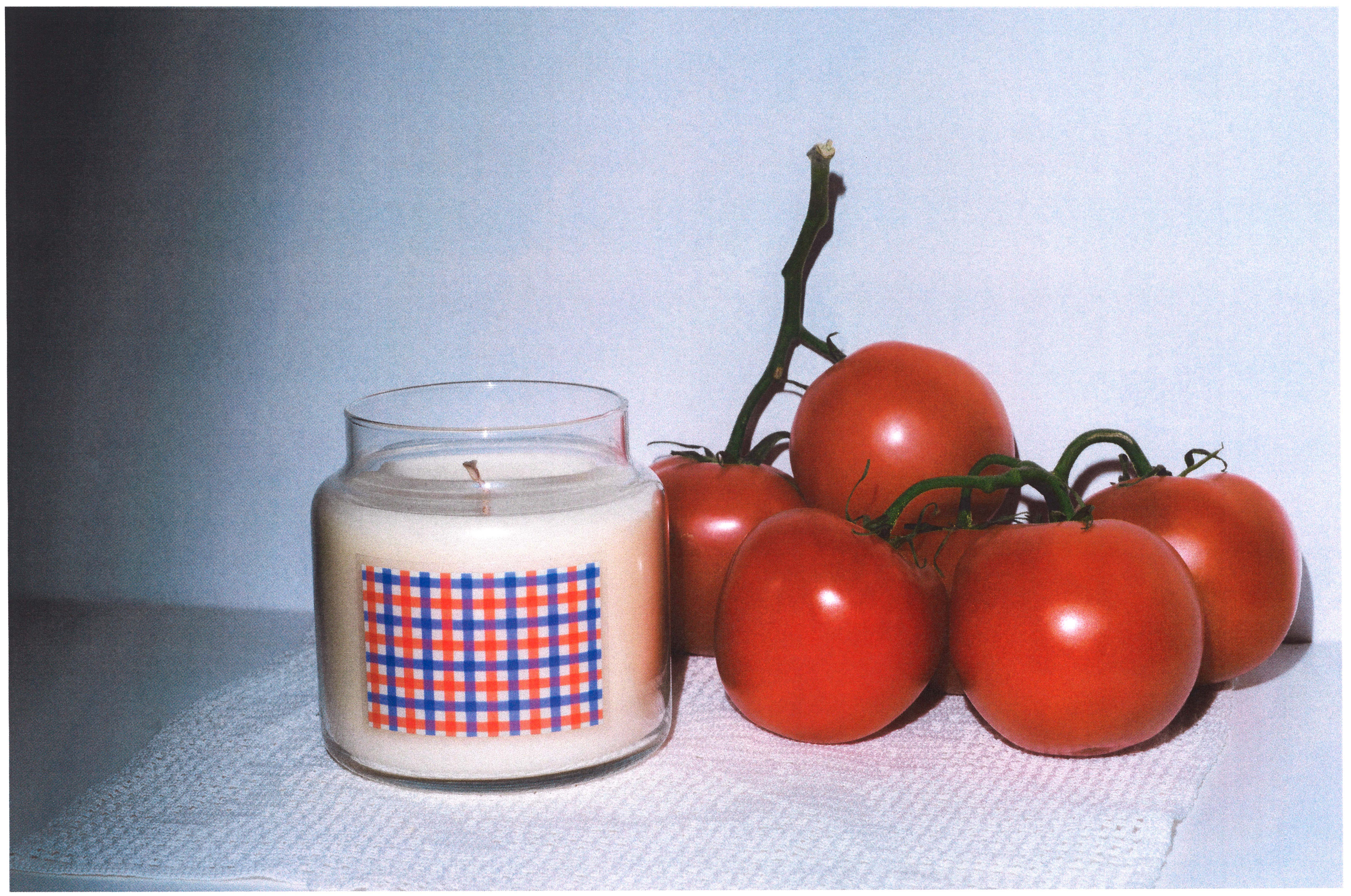 A candle next to a bunch of tomatoes