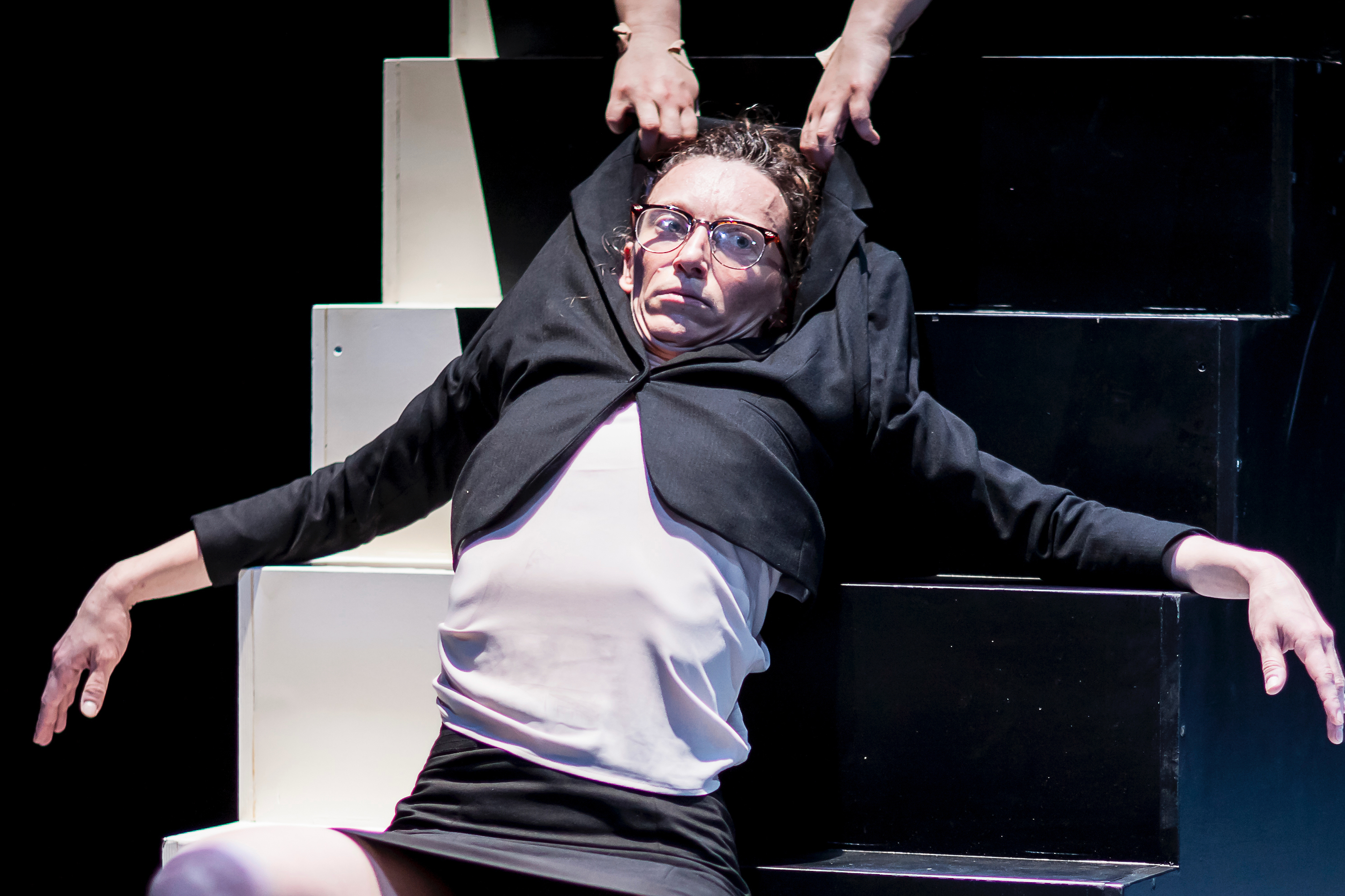 Image 6 of 10: A woman in a black skirt suit being pulled up stairs