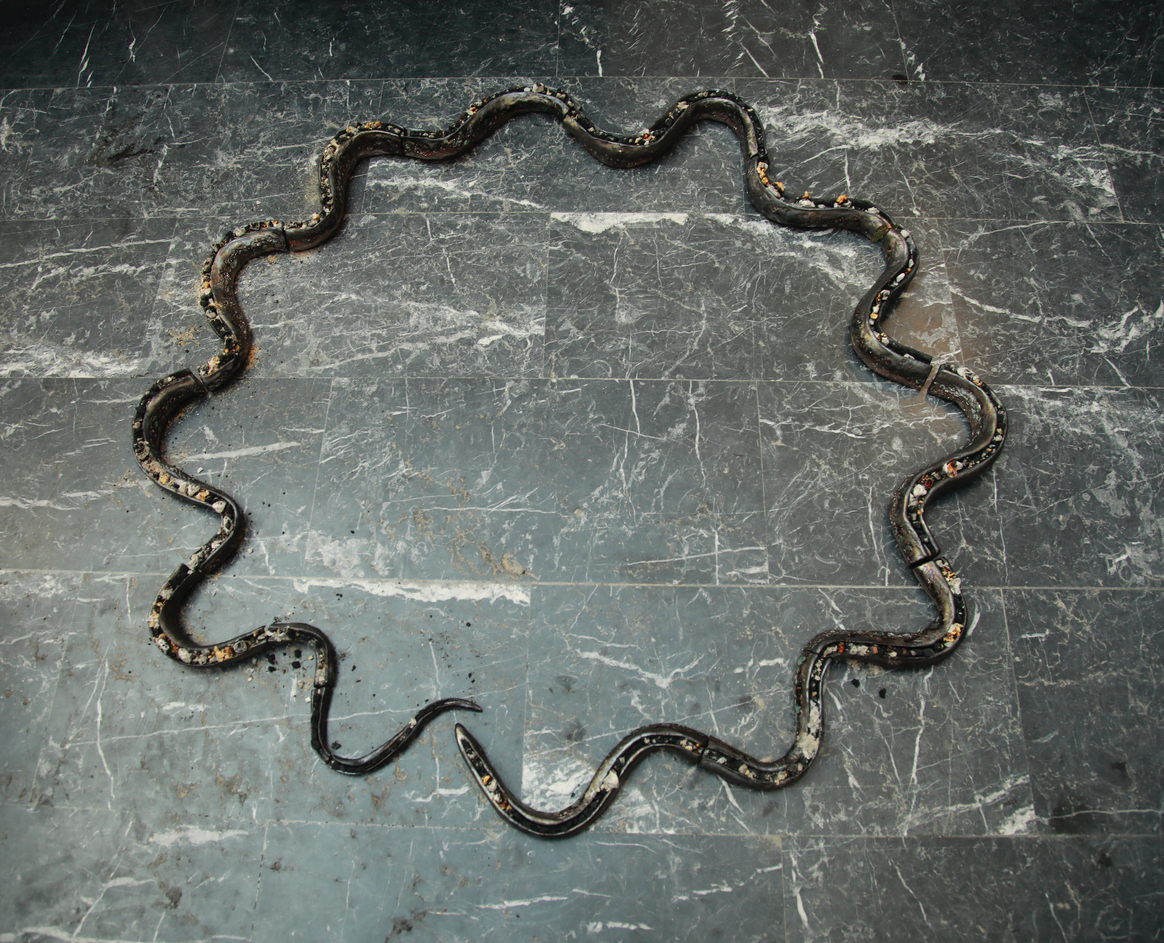 Smoke Compositions | Untitled (Theriaca Censer) 2022 Camphor, Ammonium Gum, and onycha operculum, ceramic "Smoke Compositions" is a ritual sculpture that takes the form of a penetrable censer in the shape of a modular, vibrating, zigzagging serpent, forming an ouroboros where incense burns. The shape of the censer evokes the winding course of the Gadalquivir River, where the work was activated, and the way the smoke rises and fills the air. The work also alludes to theriac, an ancient panacea made from various ingredients, including snakeskin, which was believed to cure most ailments. "Smoke Compositions" invites us to consider the intertwined histories of smell, medicine, commerce, and belief. The sculpture is a meditation on the enduring power of smell and its role in healing practices, as well as its associations with trade and exchange. By referencing theriacology, the work also speaks to the current fascination with panaceas and the promise of a universal cure.