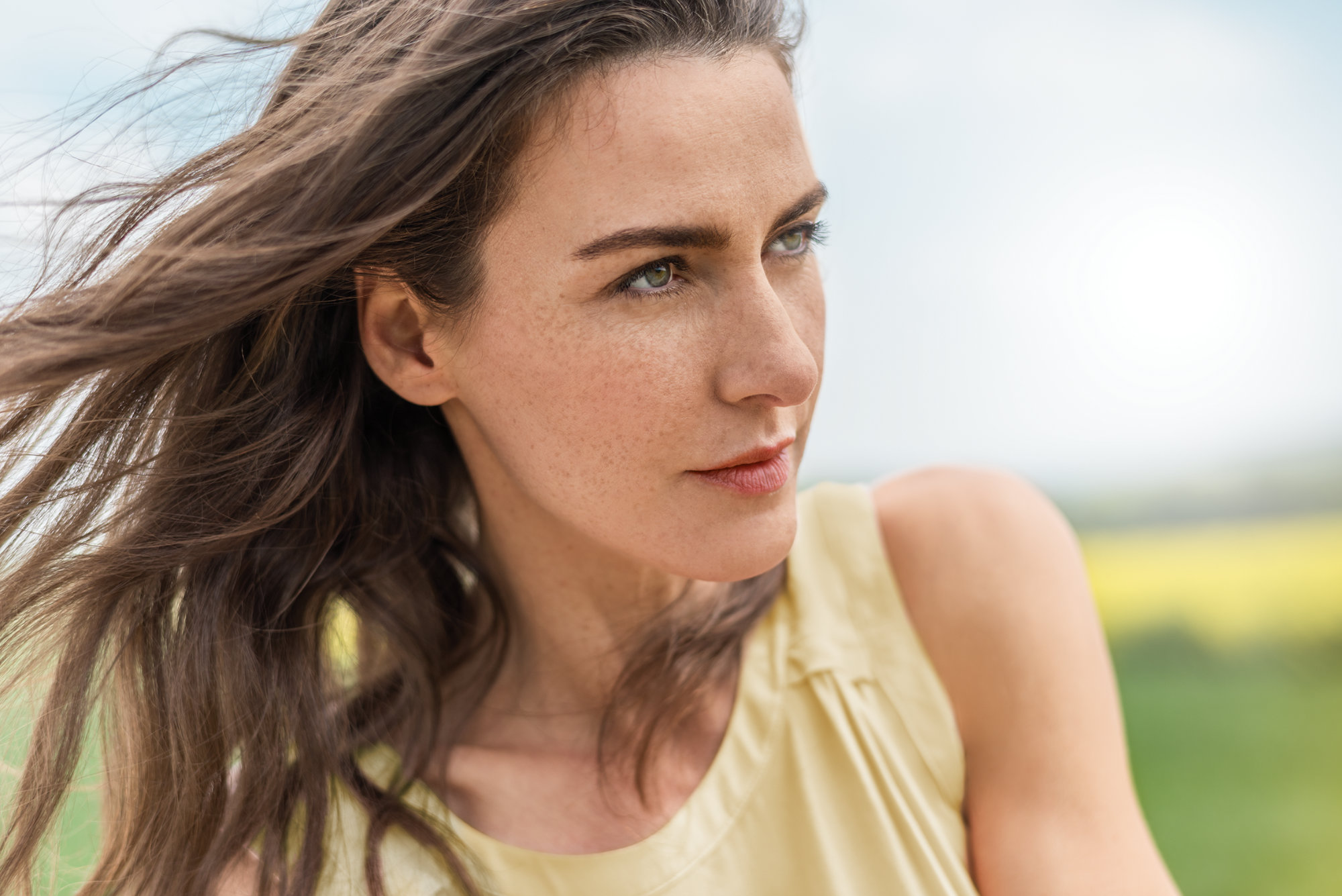 Portrait einer jungen Frau.Wind im langen Haar, gelbes Kleid.