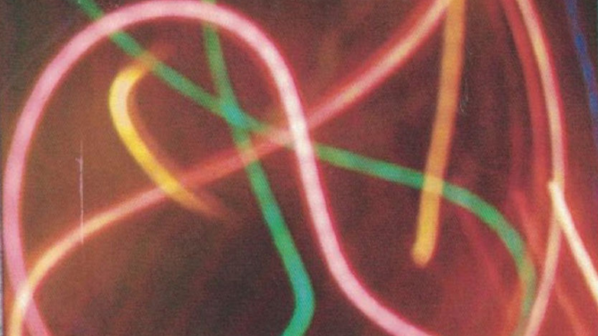 ID: Light photography of green, orange and red neon swirls against a dark background.
