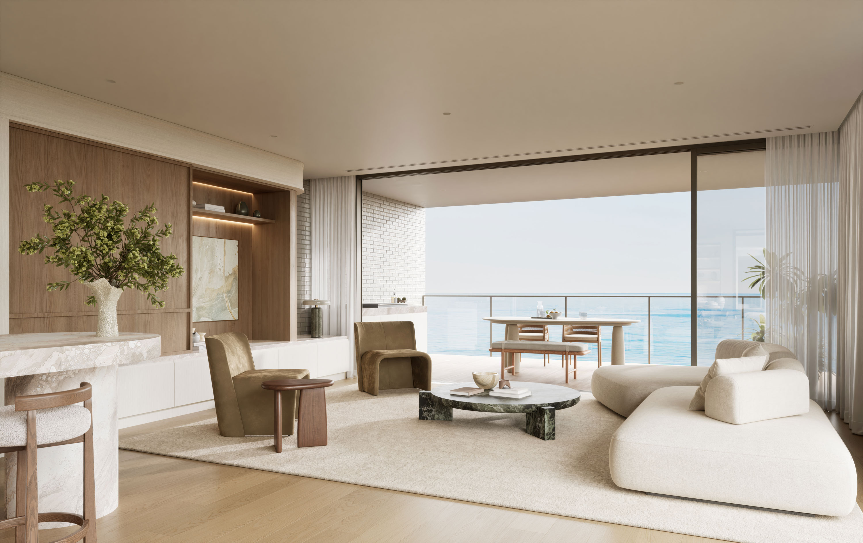 Spacious, light-filled luxury living room with neutral tones, warm wood accents, and plush modern furniture. Floor-to-ceiling glass doors open to a wide balcony overlooking the ocean, blending indoor and outdoor living with seamless views of sparkling blue water.