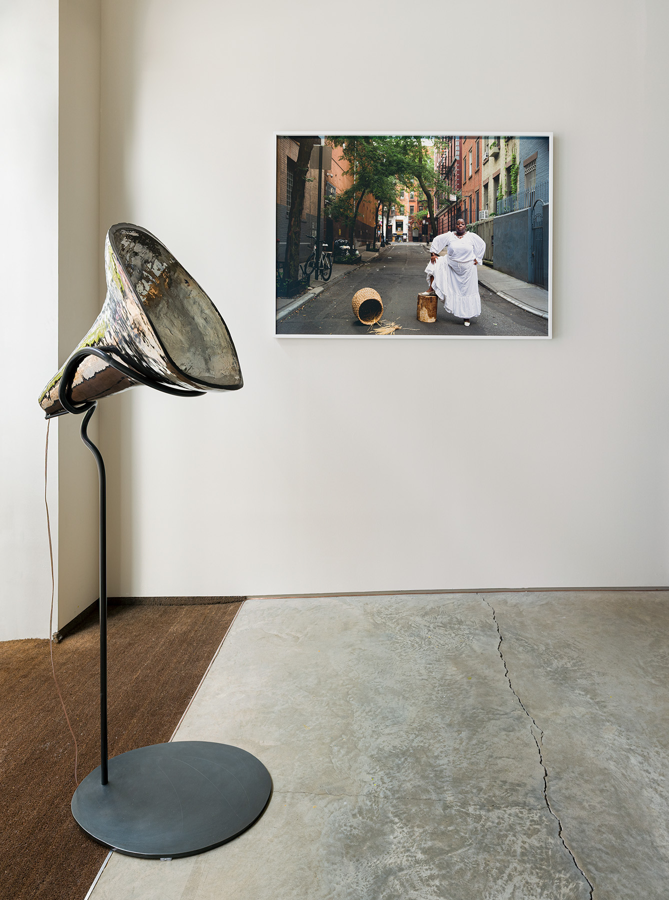 Front: Andrea Ray, The Sound of Women’s Rights, 2020/2025. Stoneware with glaze, steel with finish, speaker, audio equipment, 5-minute audio on loop, 24 x 21 x 62 inches. Courtesy of the artist. Back: Nona Faustine, "Dorothy Angola, Stay Free, In Land Of the Blacks, Minetta Lane, the Village, NYC," 2021. Pigment print, 40 x 60 inches. Courtesy of The Estate of Nona Faustine and Higher Pictures.Photo by Etienne Frossard.