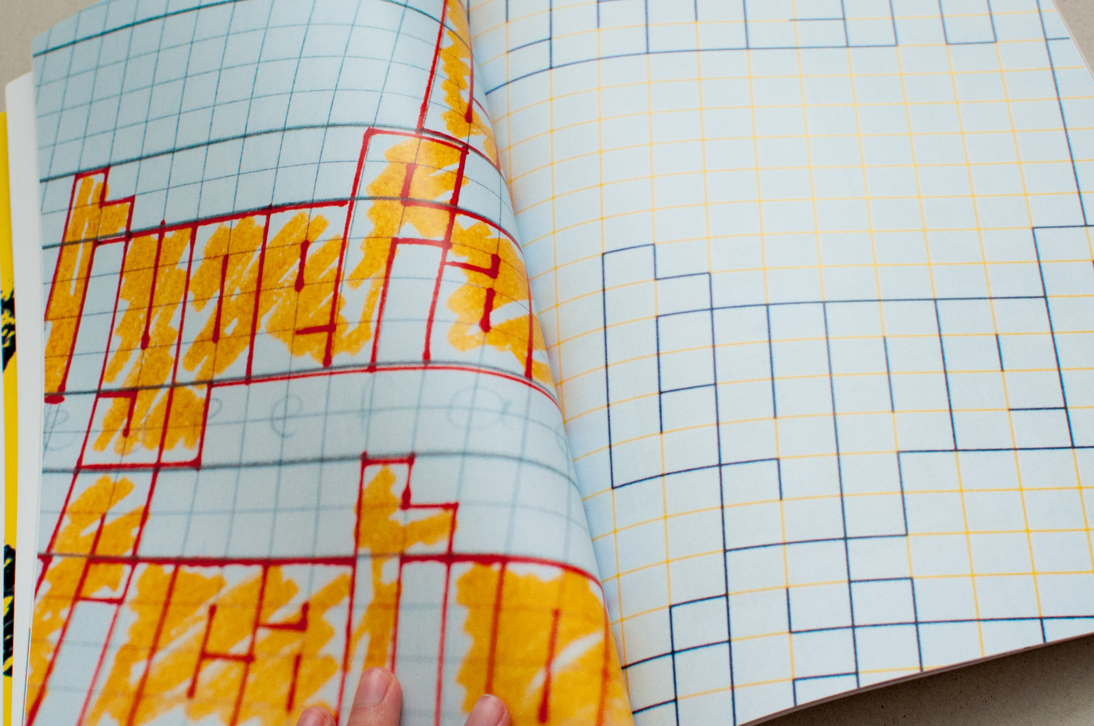 An image of a spread of a book with hand drawn geometric letters on a grid. 