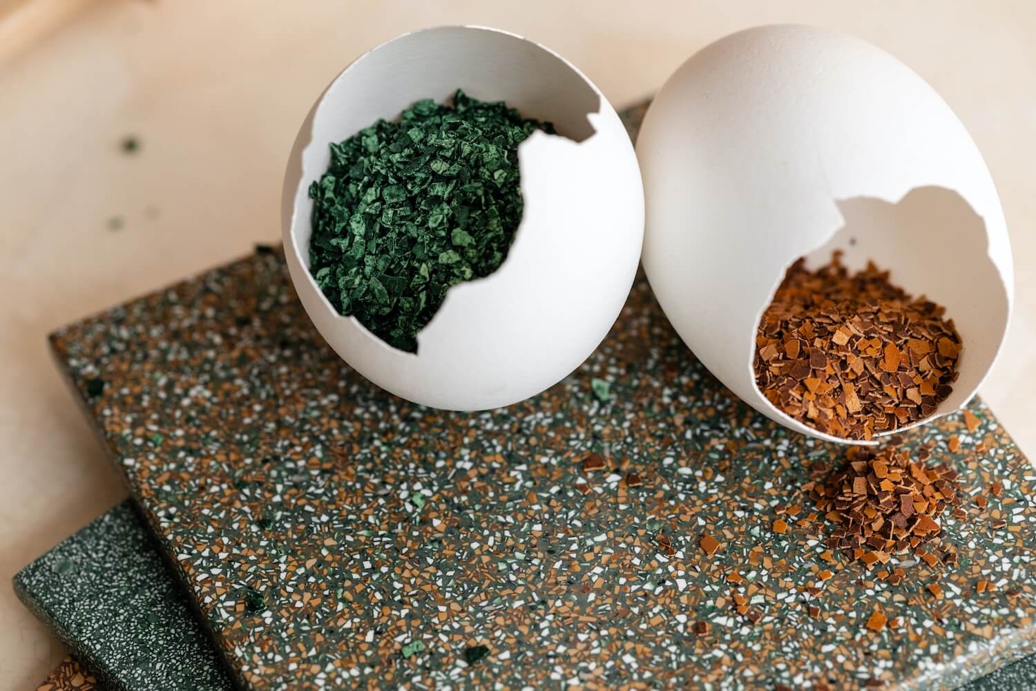Two empty egg shells and natural material samples in green and orange tones