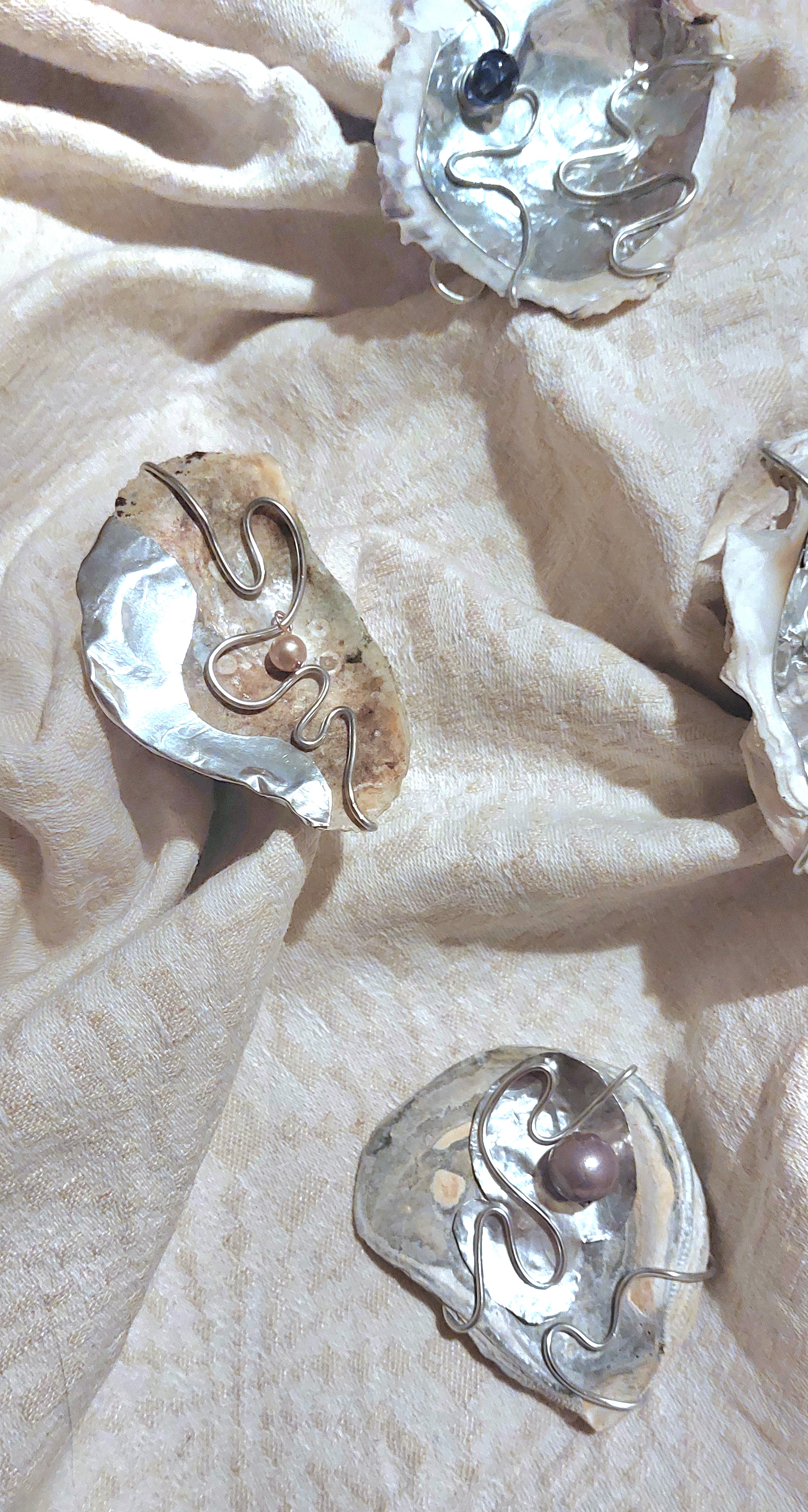 V&auml;ggh&auml;ngen: ostronskal, &aring;terbrukat aluminium, glasp&auml;rlor, akrylp&auml;rlor, aluminiumtr&aring;d.