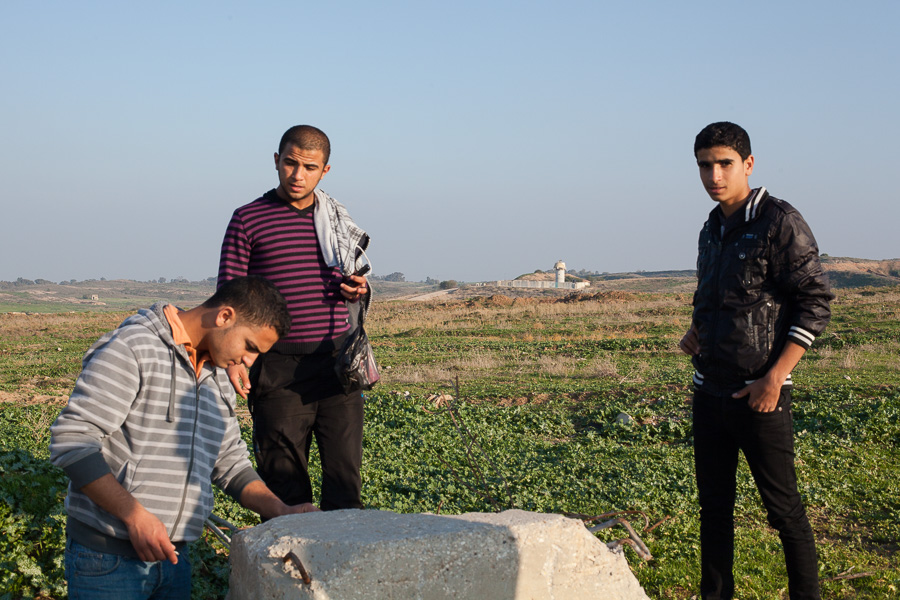 Beit Hanoun, d&eacute;cembre 2012. Cette borne en b&eacute;ton sert de cible d'entra&icirc;nements au militaires dans la tour. Depuis la tr&ecirc;ve, les Palestiniens peuvent acc&eacute;der &agrave; la buffer zone...de mani&egrave;re al&eacute;atoire. En effet, les soldats isra&eacute;liens ouvrent encore le feu sur les personnes qui s'approchent trop de la ligne de barbel&eacute;s. Quelques minutes plus tard, ces jeunes seront la cible de tirs. Heureusement, aucun ne sera bless&eacute;. Situ&eacute;e apr&egrave;s la kill zone o&ugrave; toute personne qui entre est abattue &agrave; vue, la buffer zone, large de 300 &agrave; 500m, est faite de champs appartenant aux fermiers. A cause des tirs isra&eacute;liens, ils ont du abandonn&eacute; les cultures sur ces terrains, par crainte de se faire toucher. Aujourd'hui, ils profitent de la tr&ecirc;ve pour r&eacute;colter les fruits des arbres laiss&eacute;s en jach&egrave;re. Au total, buffer et kill zone s'&eacute;tendent sur pr&egrave;s de 35% des terres agricoles de la Bande de Gaza.