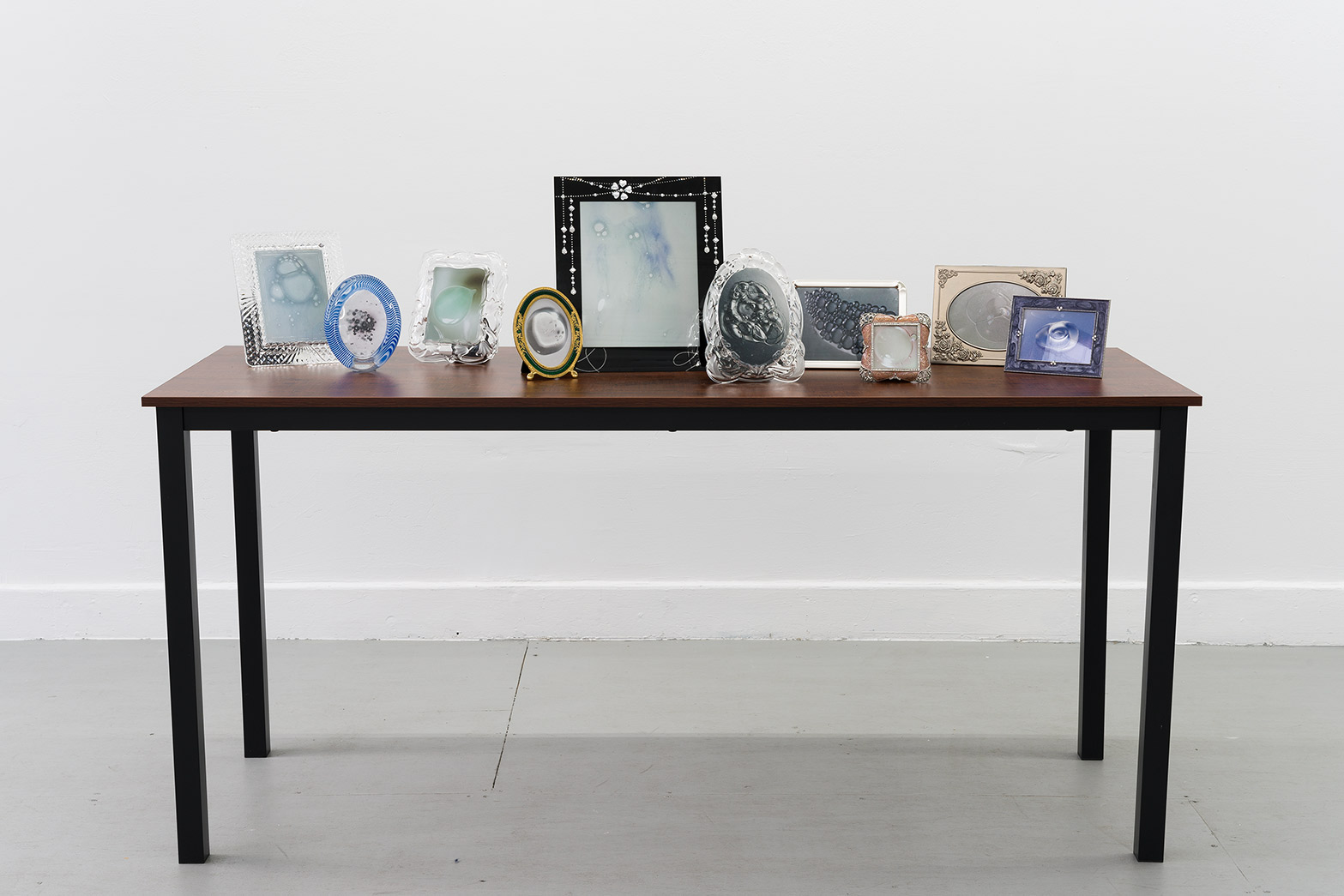 Ether, 2024, prints, frames, table, 41 x 63 x 24 in. (104.1 x 160 x 61 cm.)